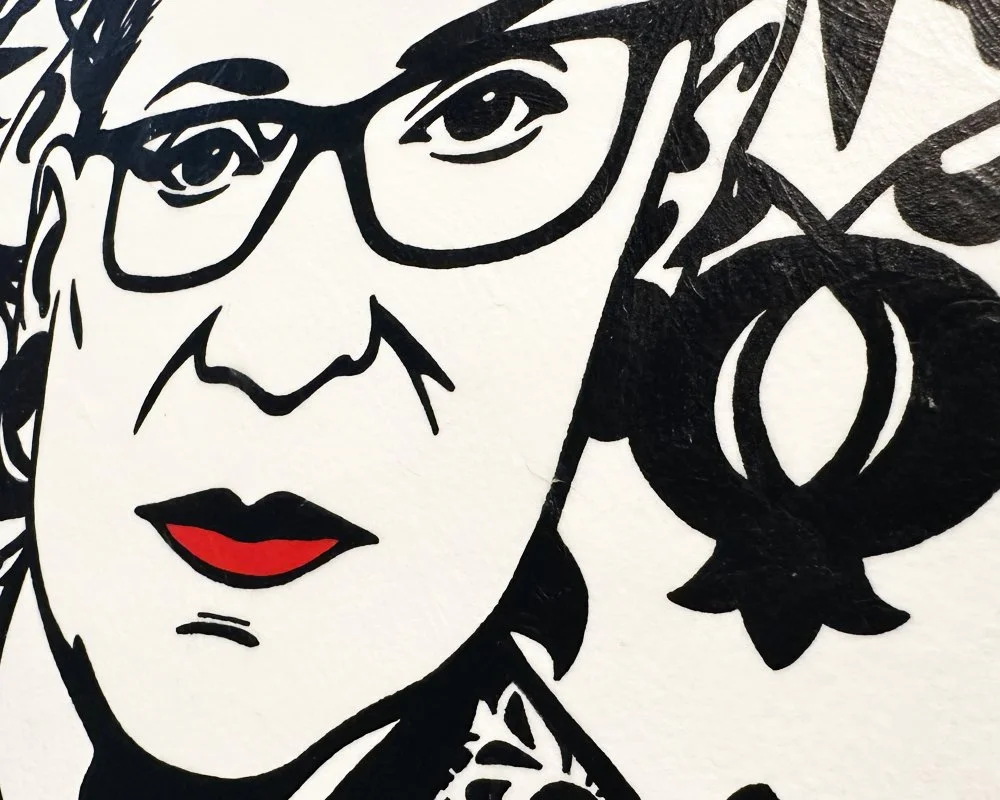 Close up detail of signature glasses and graphic black silhouette on archival cotton paper.