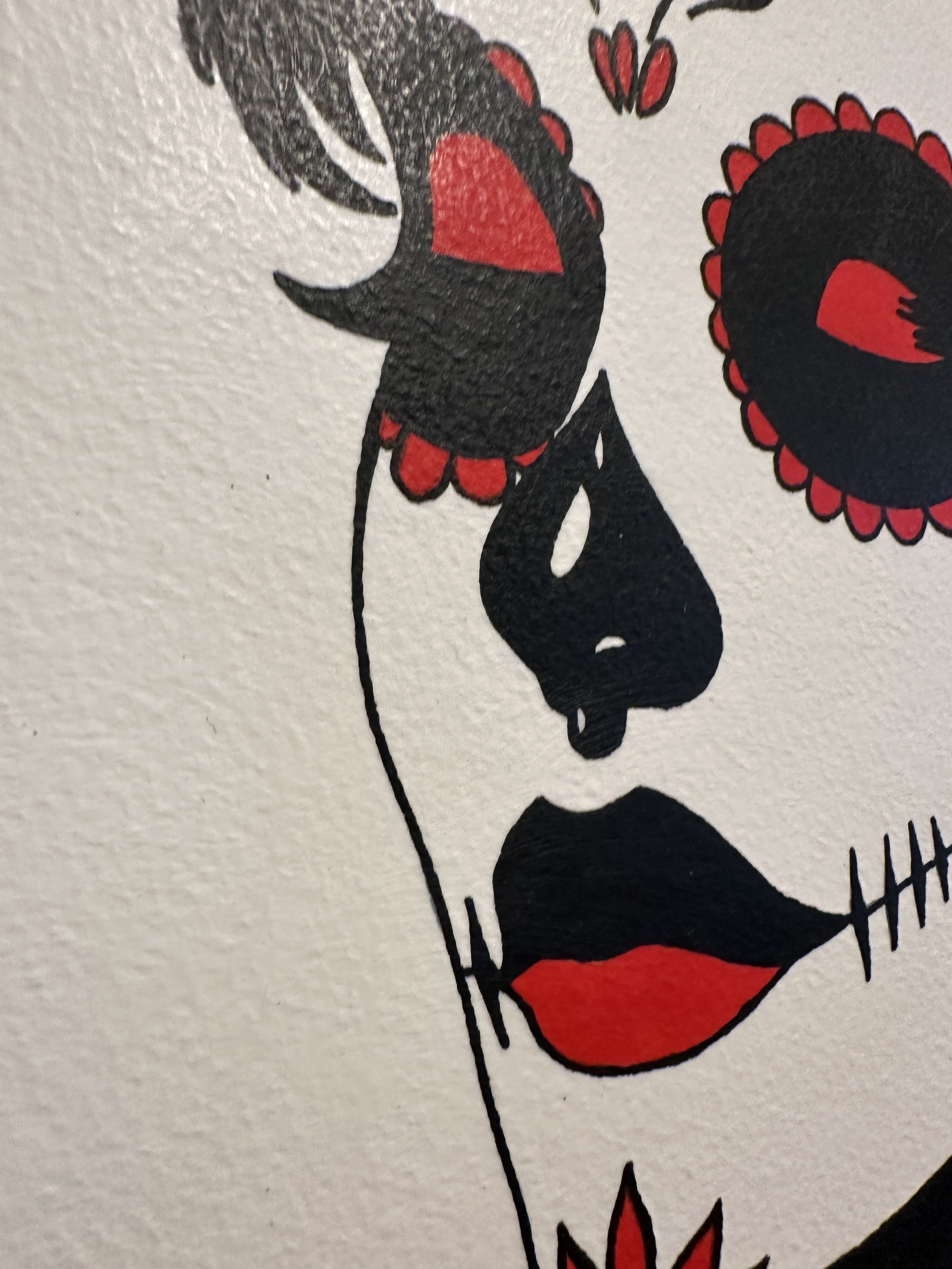 Close up detail of sugar skull makeup on a woman with short hair looking down in quiet reflection.