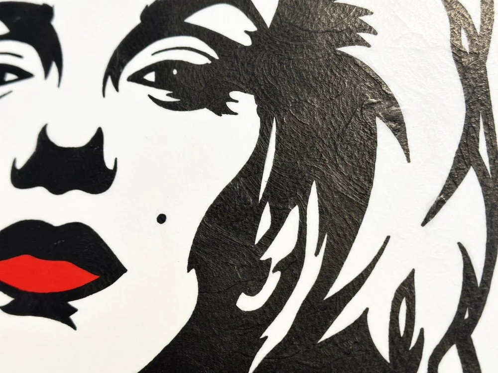 Close up macro detail of black gouache brushwork on the hair and the iconic beauty mark.