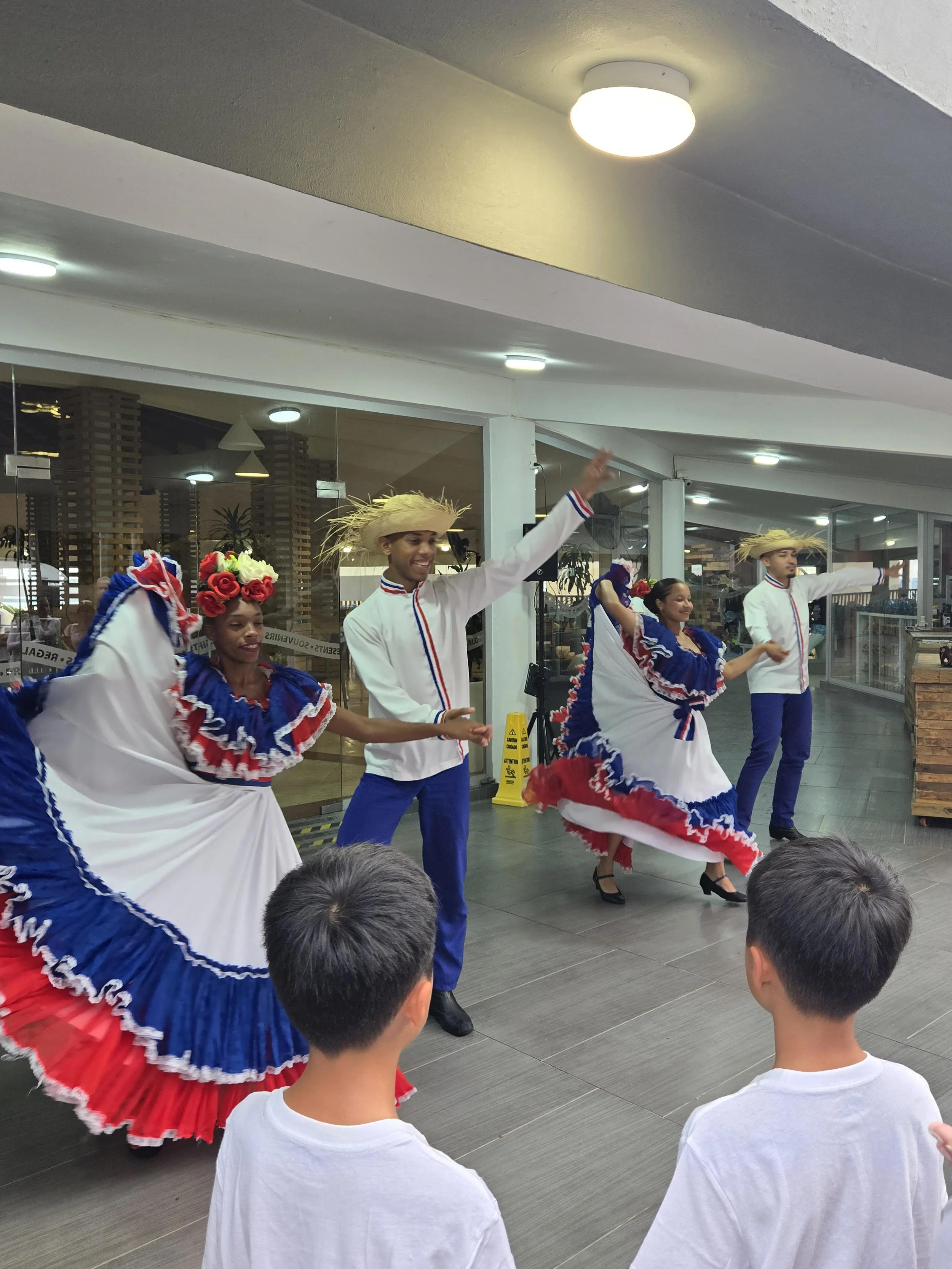 Mexican folk dancers performing in traditional costumes with children watching