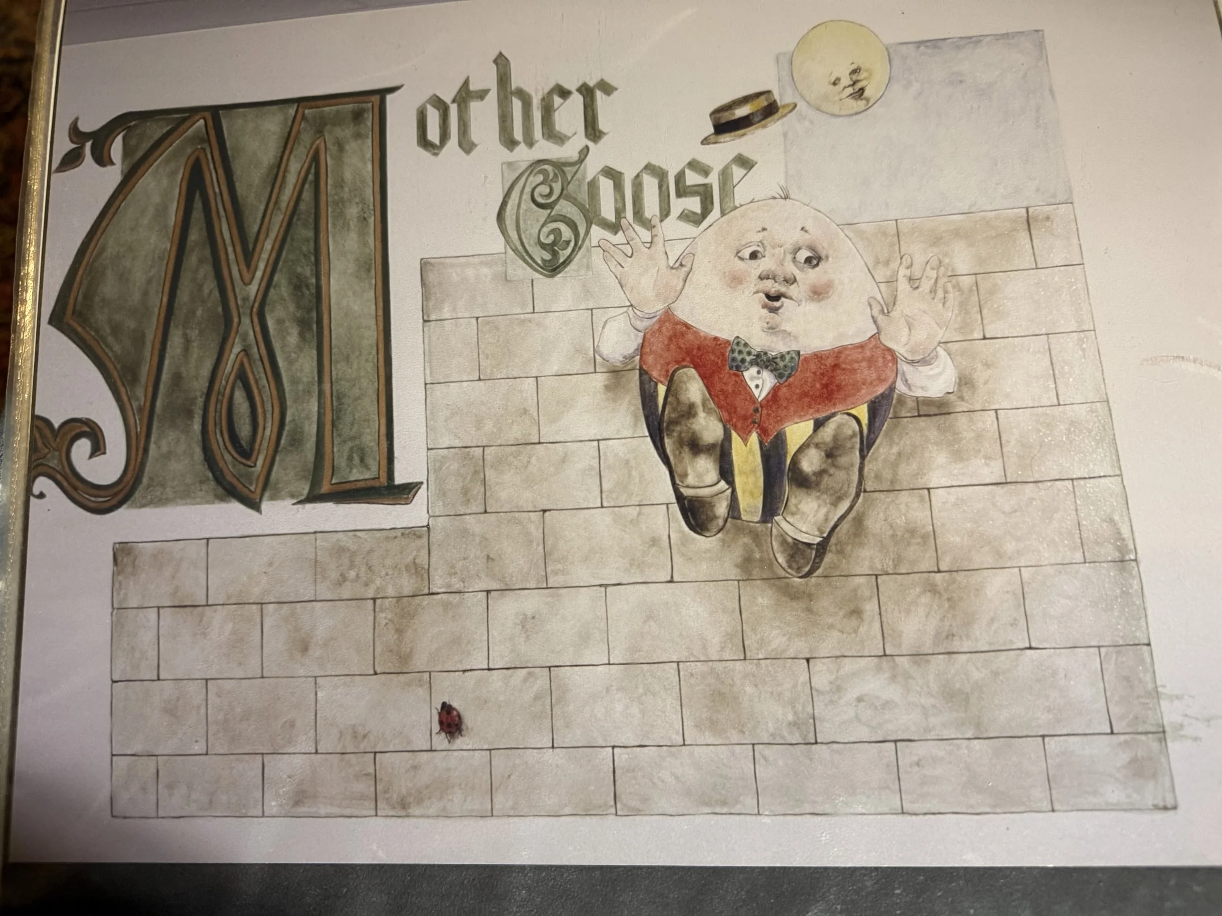 A cartoonish illustration featuring a baby with a large head, expressive eyes, and pouty lips, dressed in a tuxedo and red vest. The baby is seated in front of a brick wall, with a cartoon hat floating above the head, a moon with a face in the background, and the words 'Mother and Son' in decorative font on the left side.