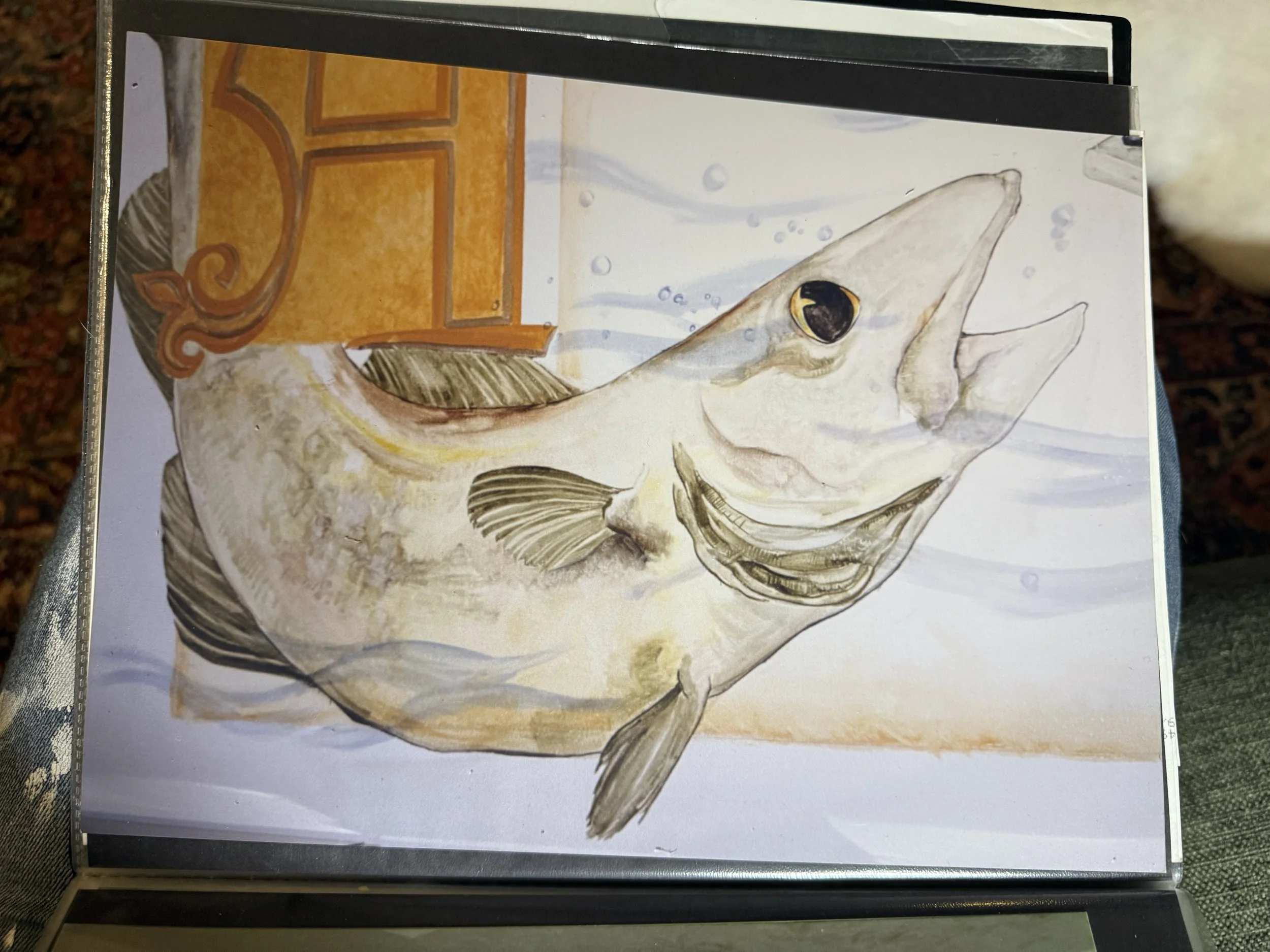 A watercolor painting of a fish with a beige body, black eye, and fins, with bubbles and swirling water in the background.