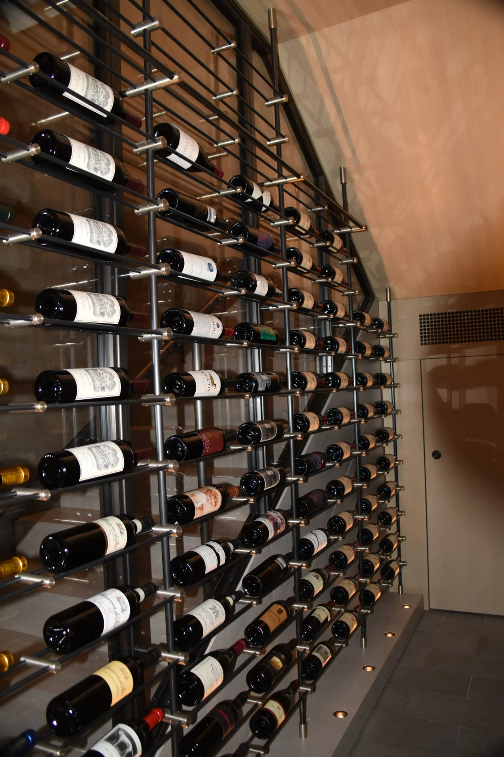 Wall-mounted wine rack filled with bottles of wine in a modern wine cellar or bar.