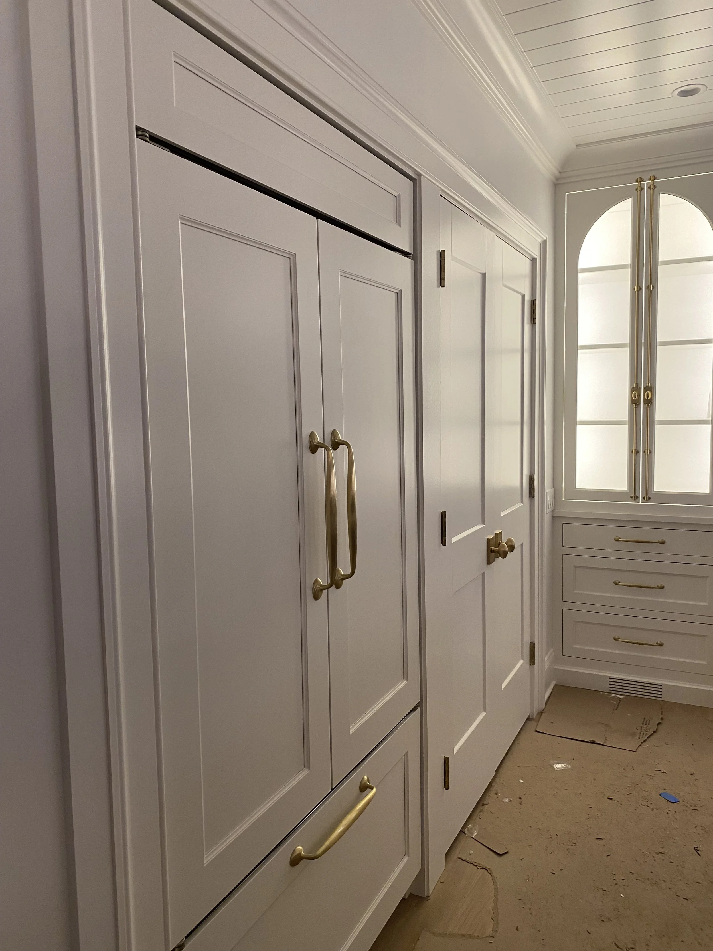 White custom cabinetry with gold hardware in a bright kitchen. 