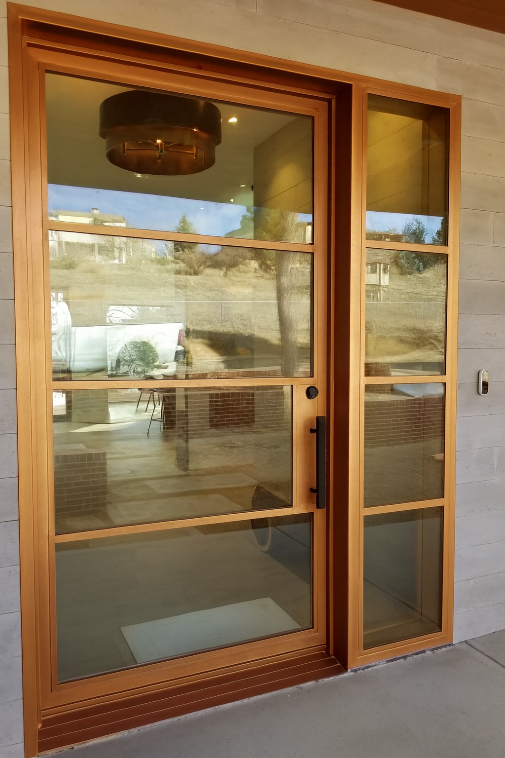 Custom copper framed glass door with black hardware and sidelights