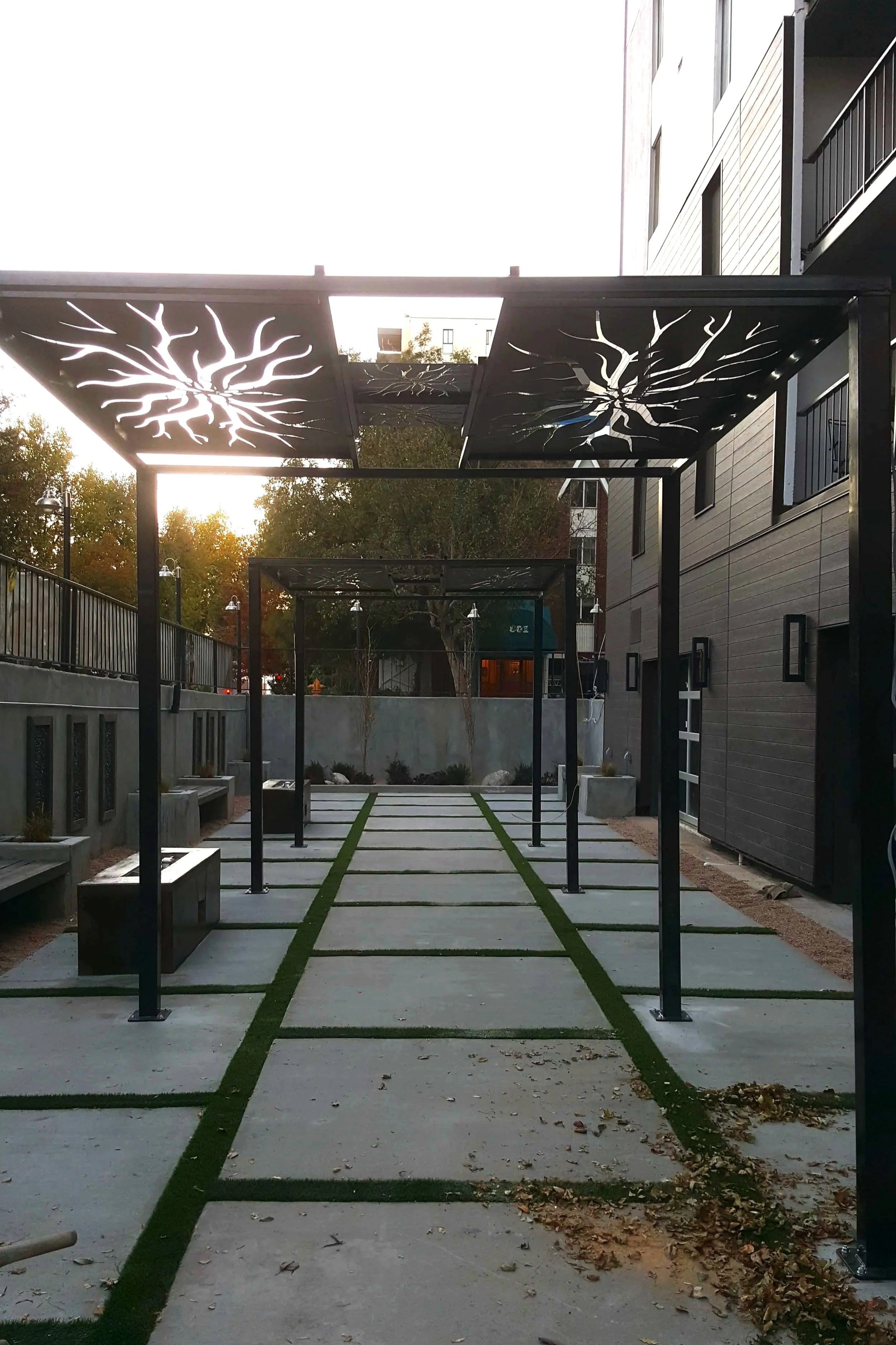 Custom steel pergola with decorative plasma cut panels installed in Denver courtyard