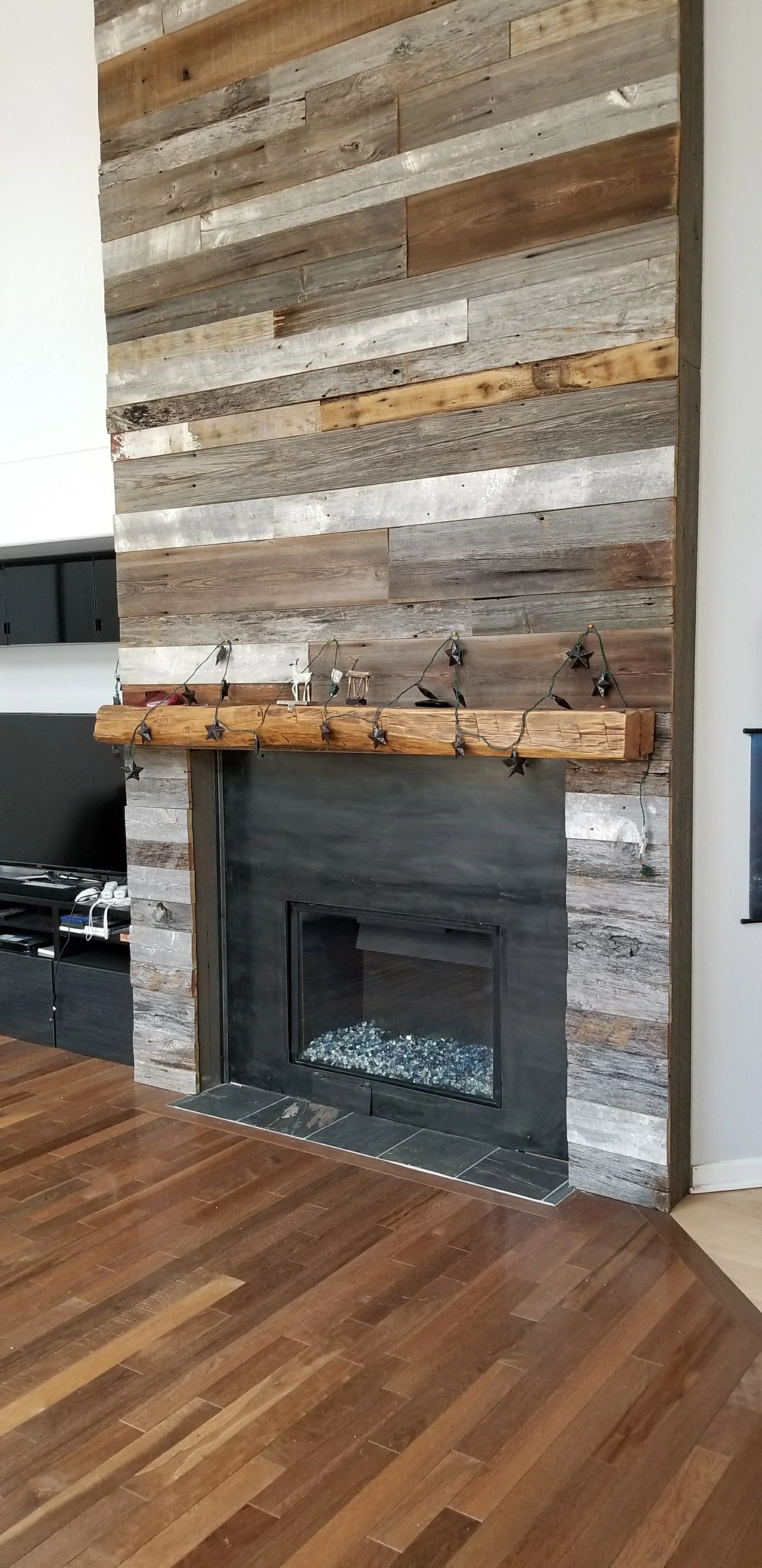 Custom steel fireplace surround with reclaimed wood accent wall in Denver residence