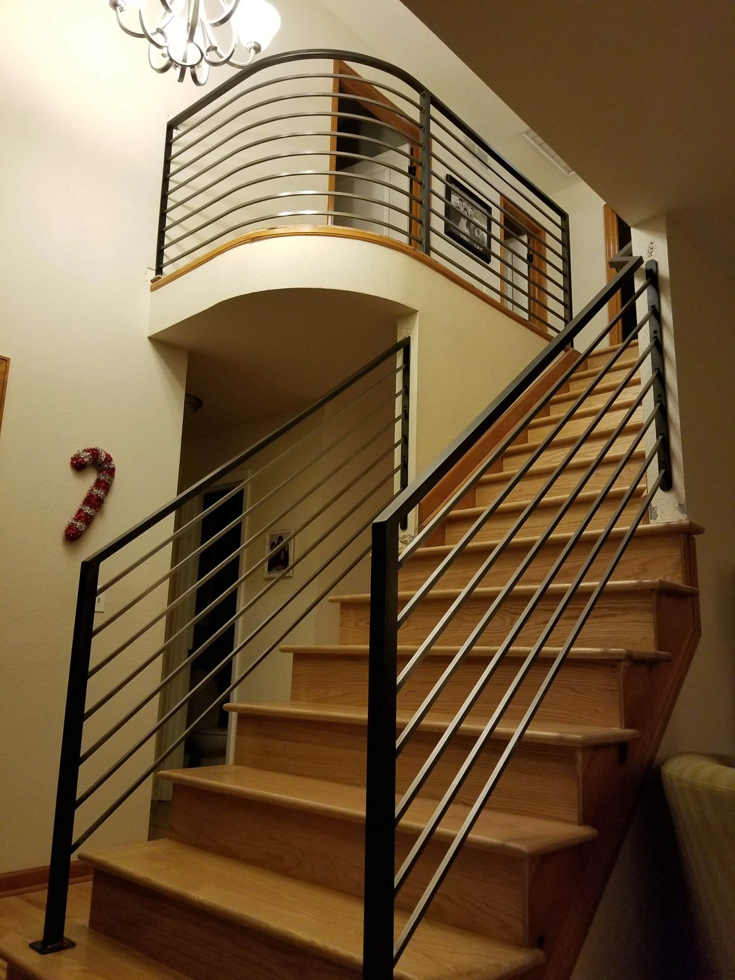 Curved interior residential railing with a curve and polished pickets and patinad posts and handrail