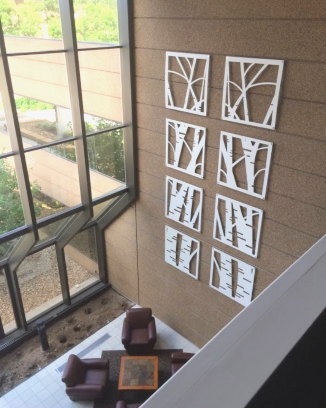 Laser cut metal wall art panels installed in multi story commercial lobby.
