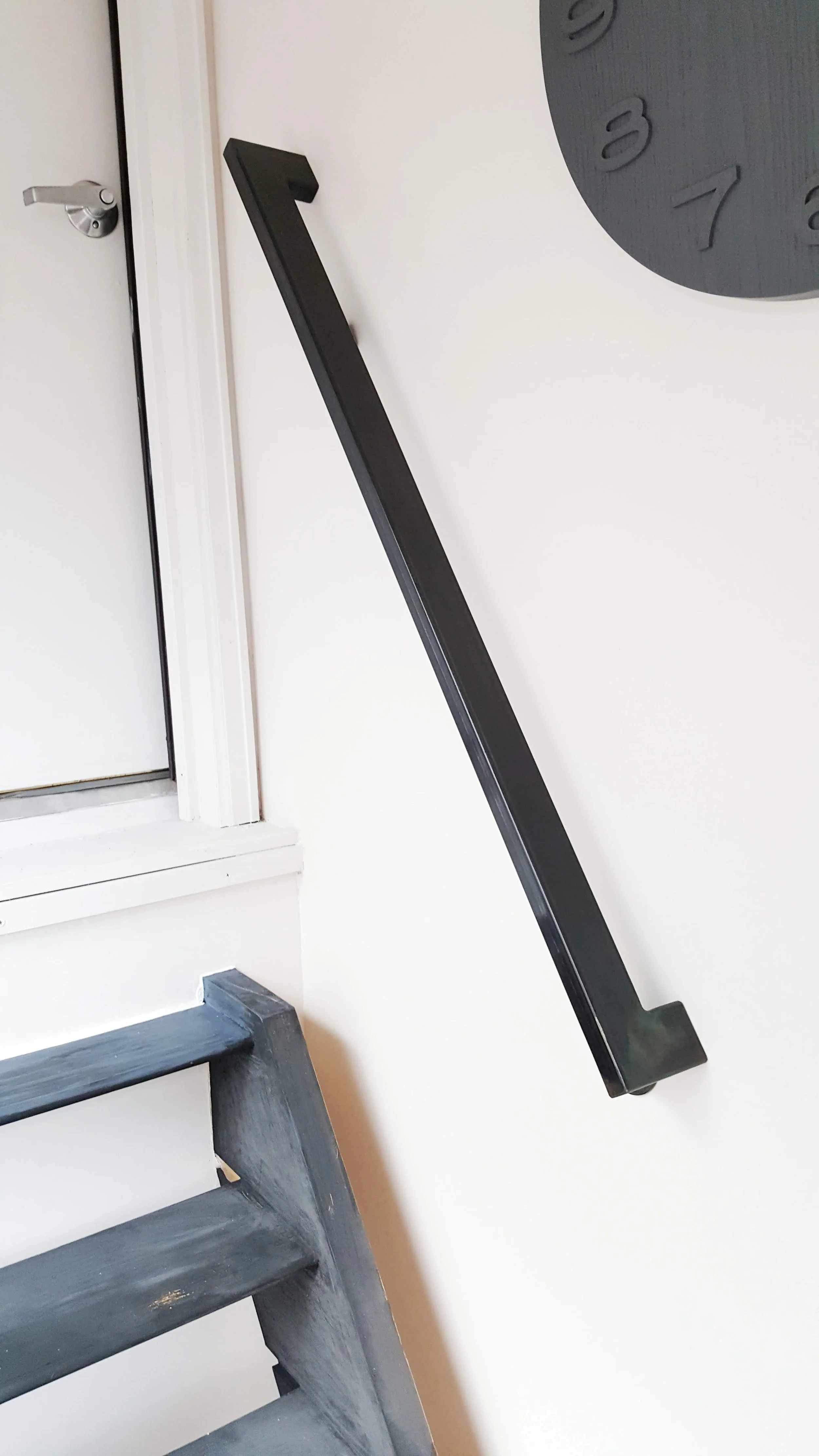 Interior handrail to attic, its metal, and there is a clock and very steep wooden stairs below