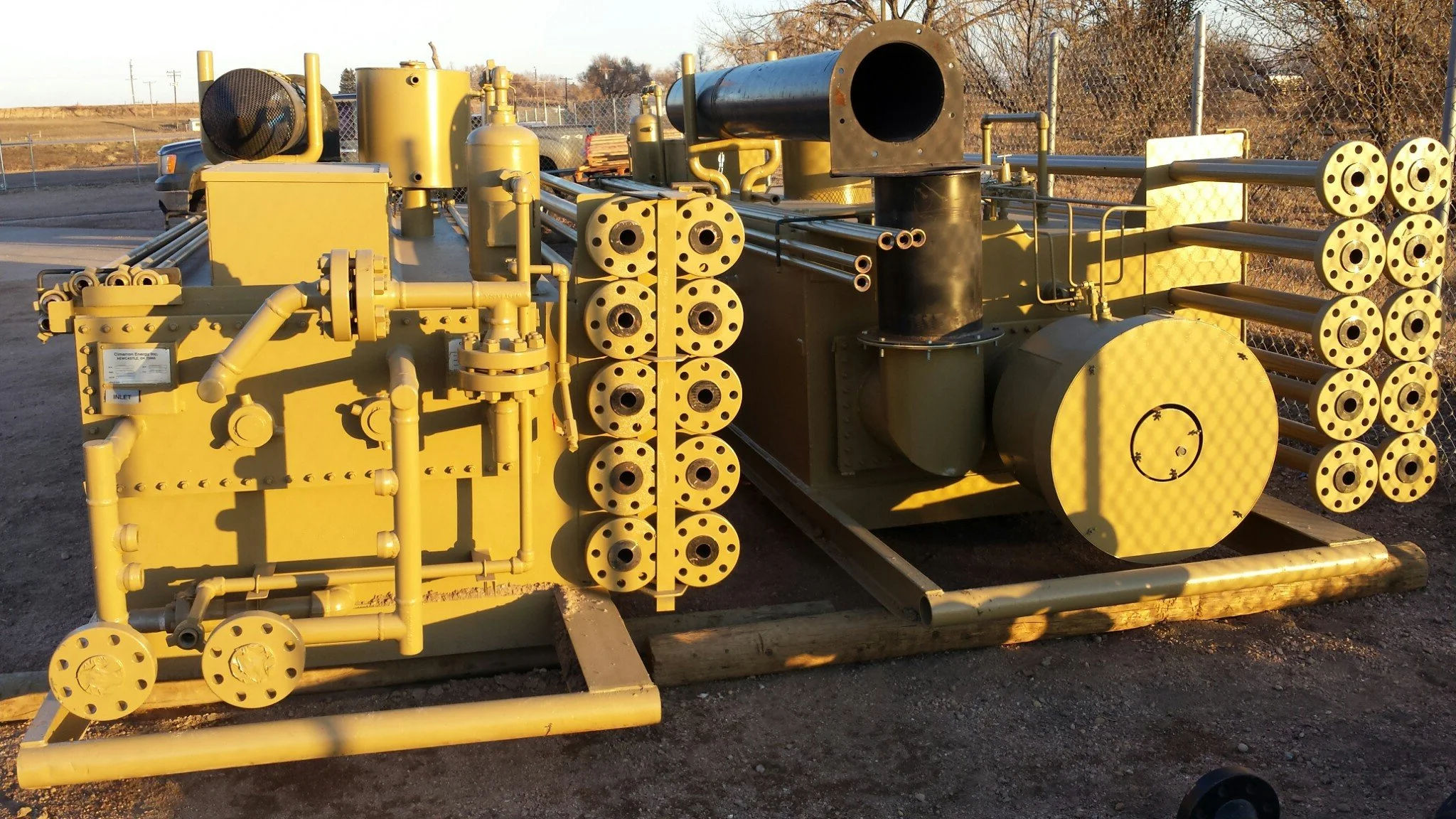 Heavy steel industrial equipment skid with flanged piping and welded structural supports in fabrication yard.