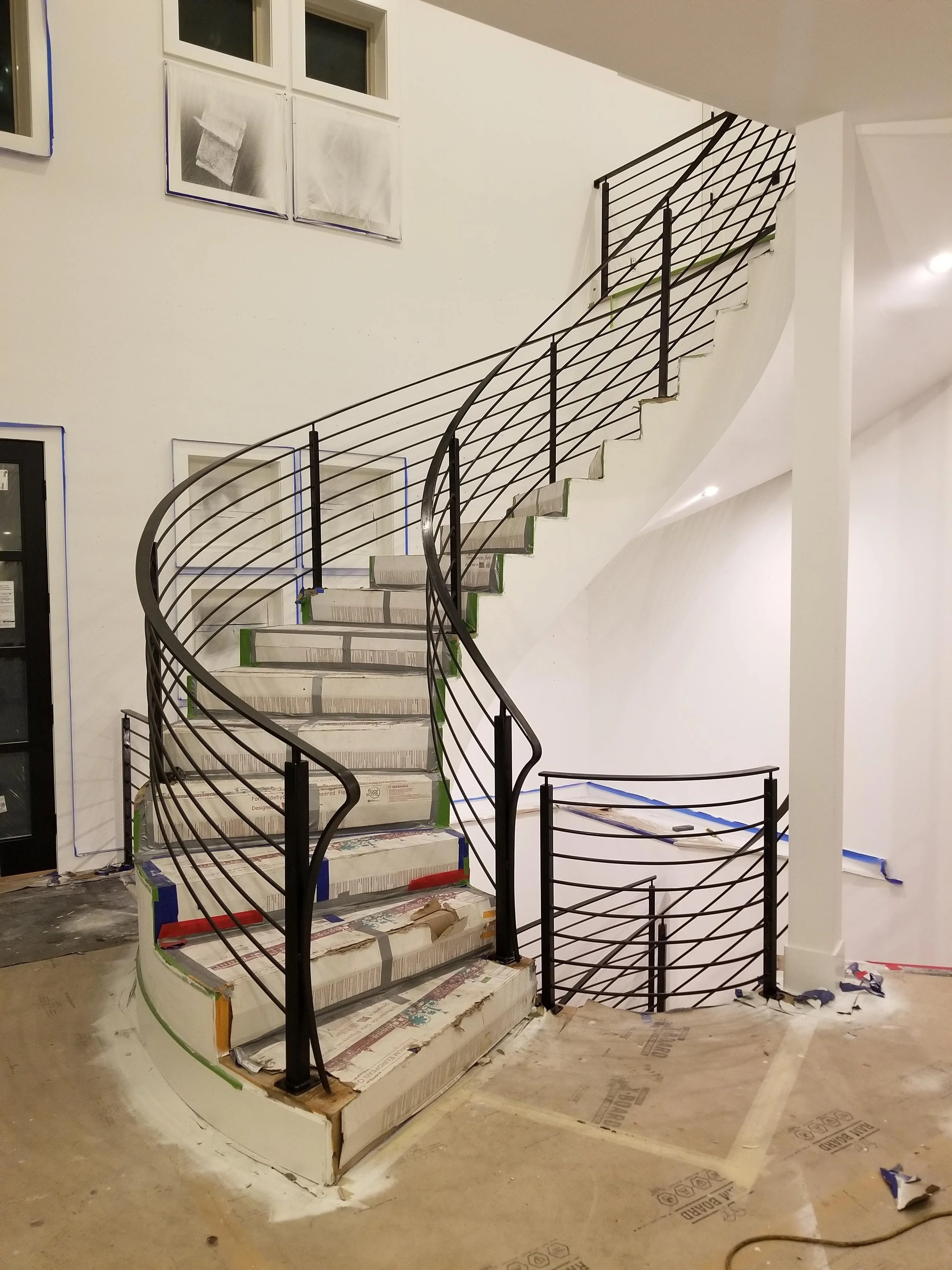 Curved metal stair railing fabricated to match a custom staircase