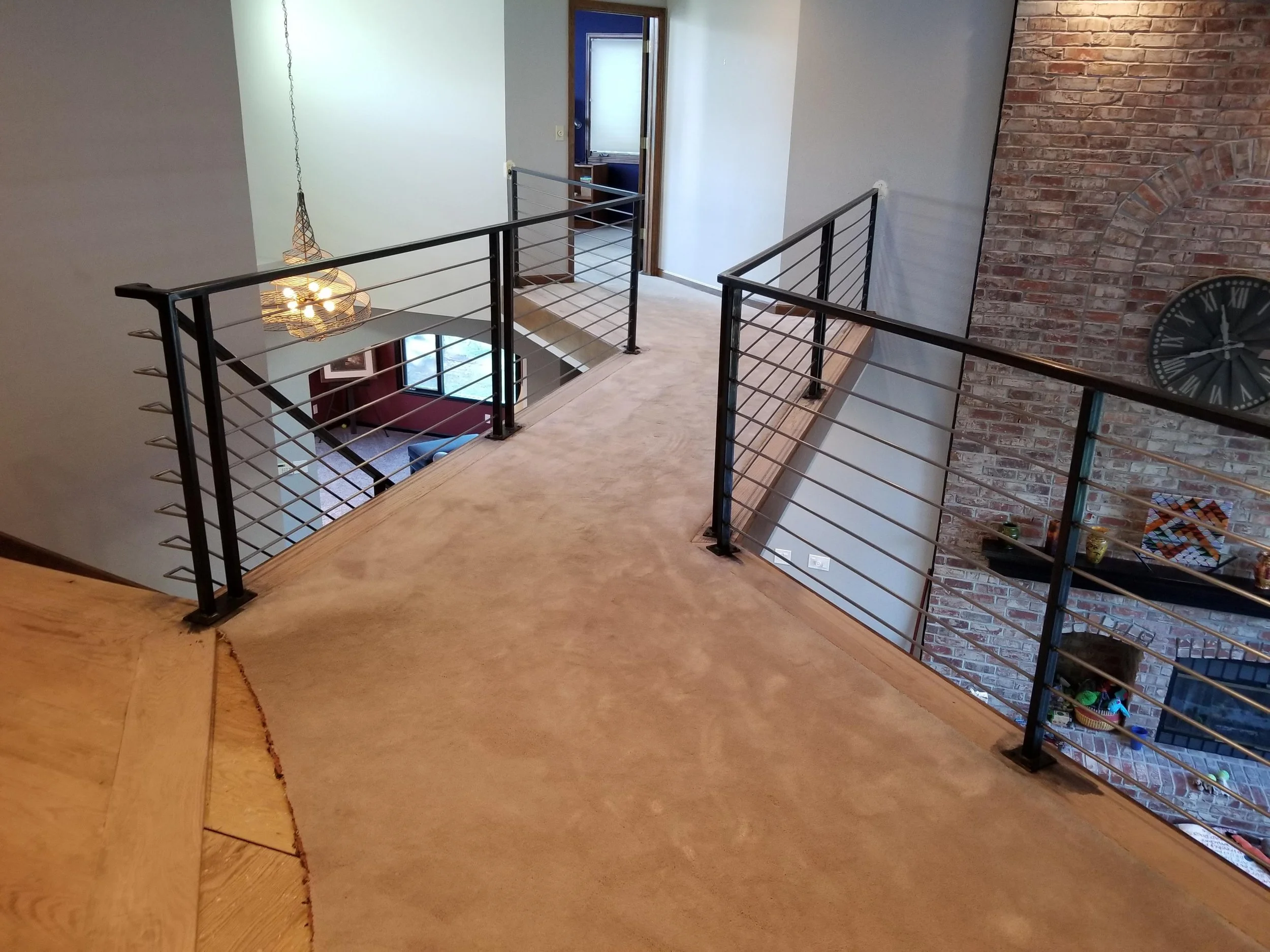 Interior view of a second-floor hall way bridge with a wooden floor, safe and secure metal railings. The railings meet all codes and requirements for the city of Broomfield Colorado of where it is located.
