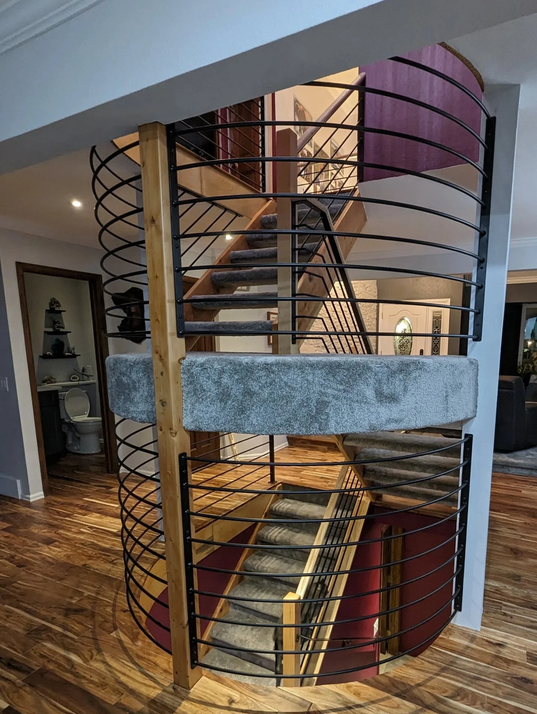 metal rounded railing with a purple wall and carpeted stairs