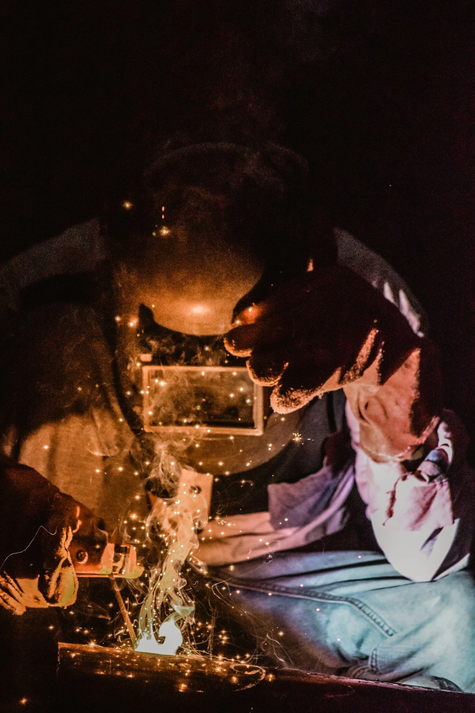 Person welding in dark with sparks flying.