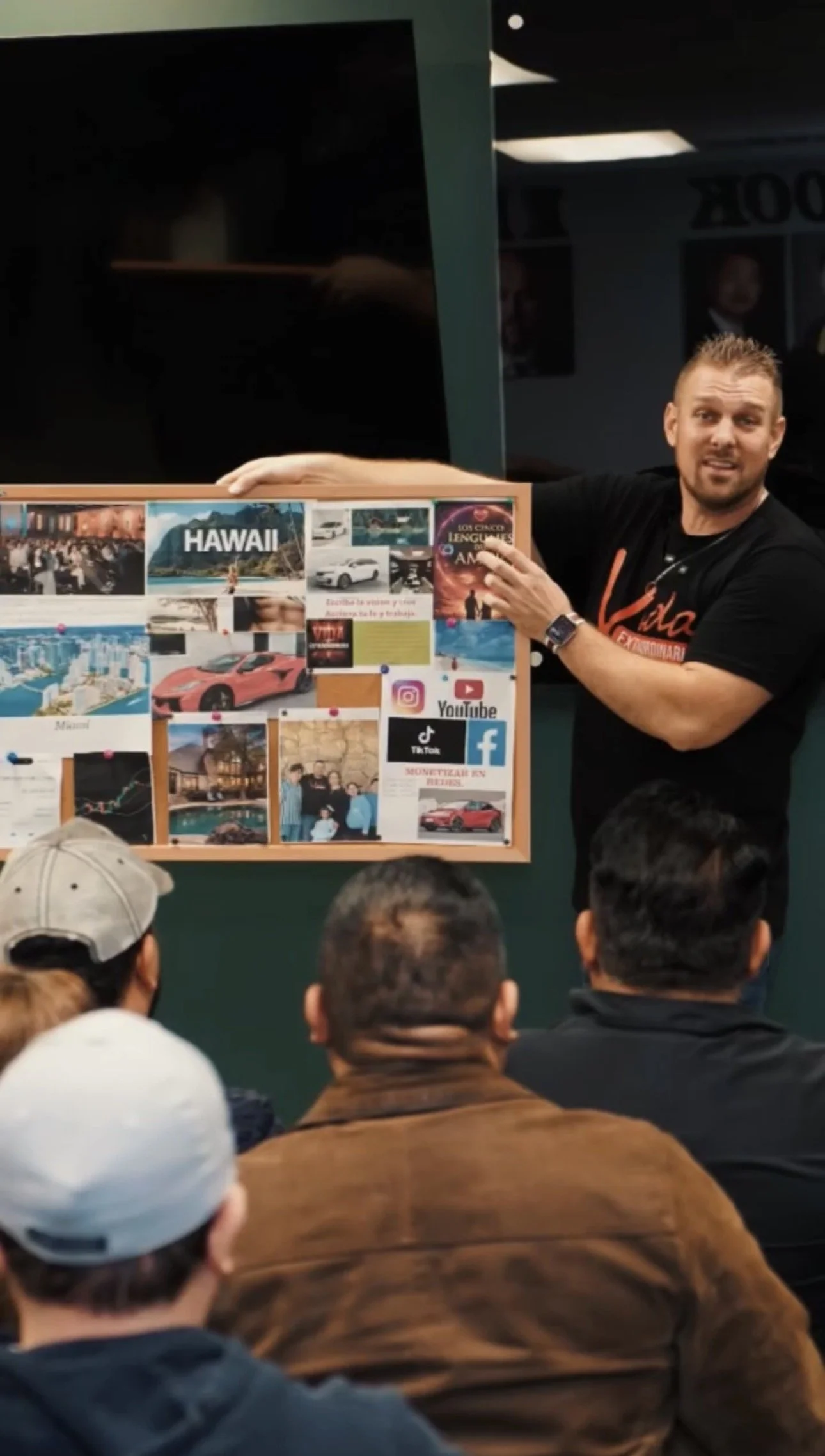 Un hombre da una presentación a un grupo de personas, mostrando un cartel que contiene imágenes de Hawái, autos deportivos, iconos de redes sociales y textos en español.