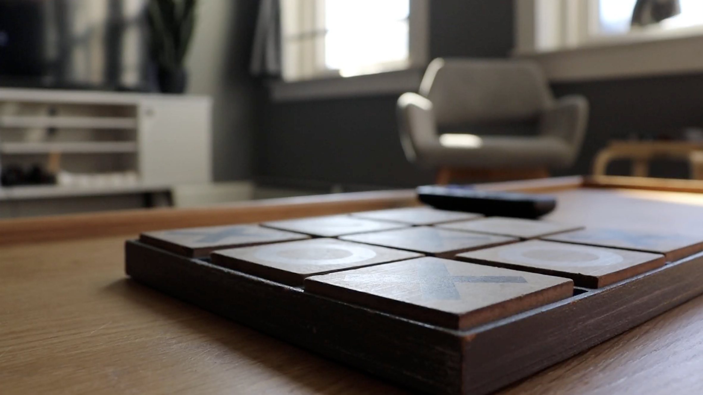 Close-up of a wooden sliding tile game with letter tiles on the table in a well-lit room.