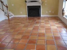 Empty room with terracotta tile floor and fireplace on the far wall.