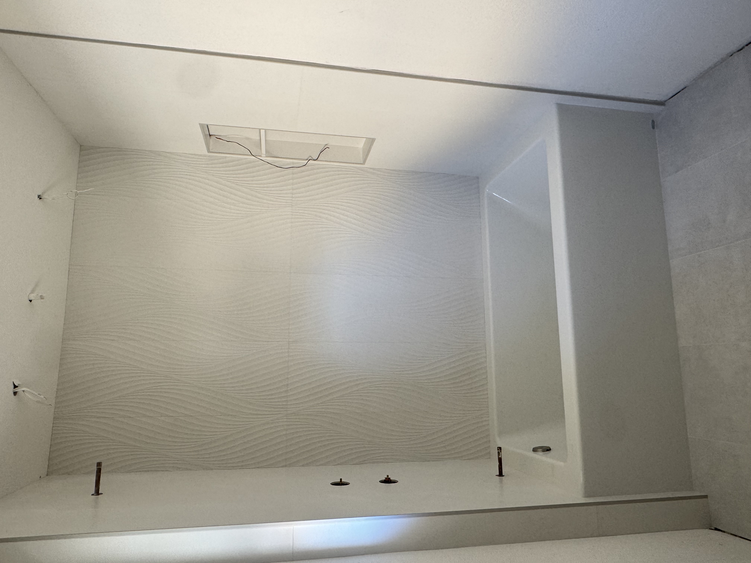  bathroom with textured white wall, built-in bathtub, and new flooring