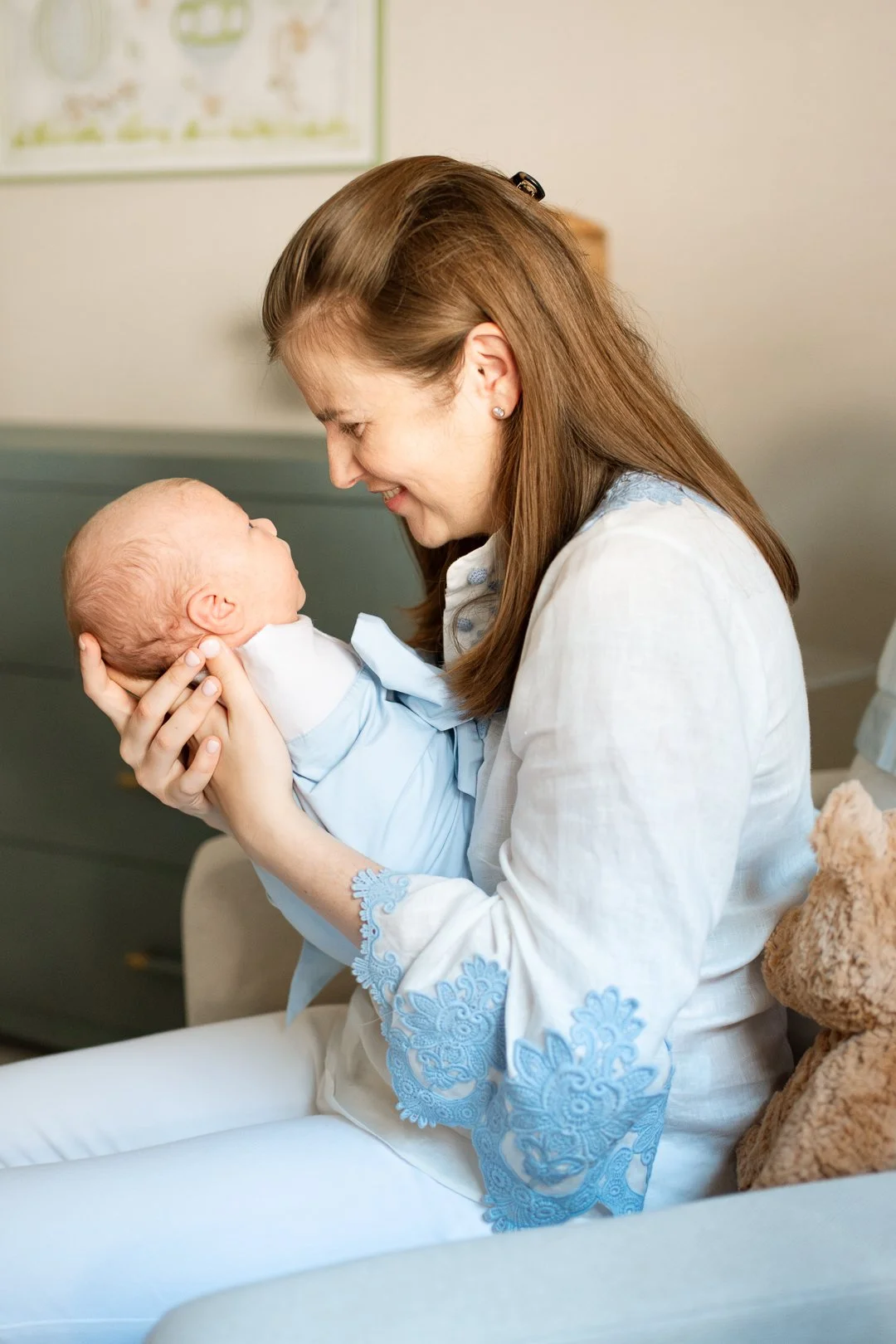 A woman holding a newborn baby close to her face, smiling at the baby in a hospital room.