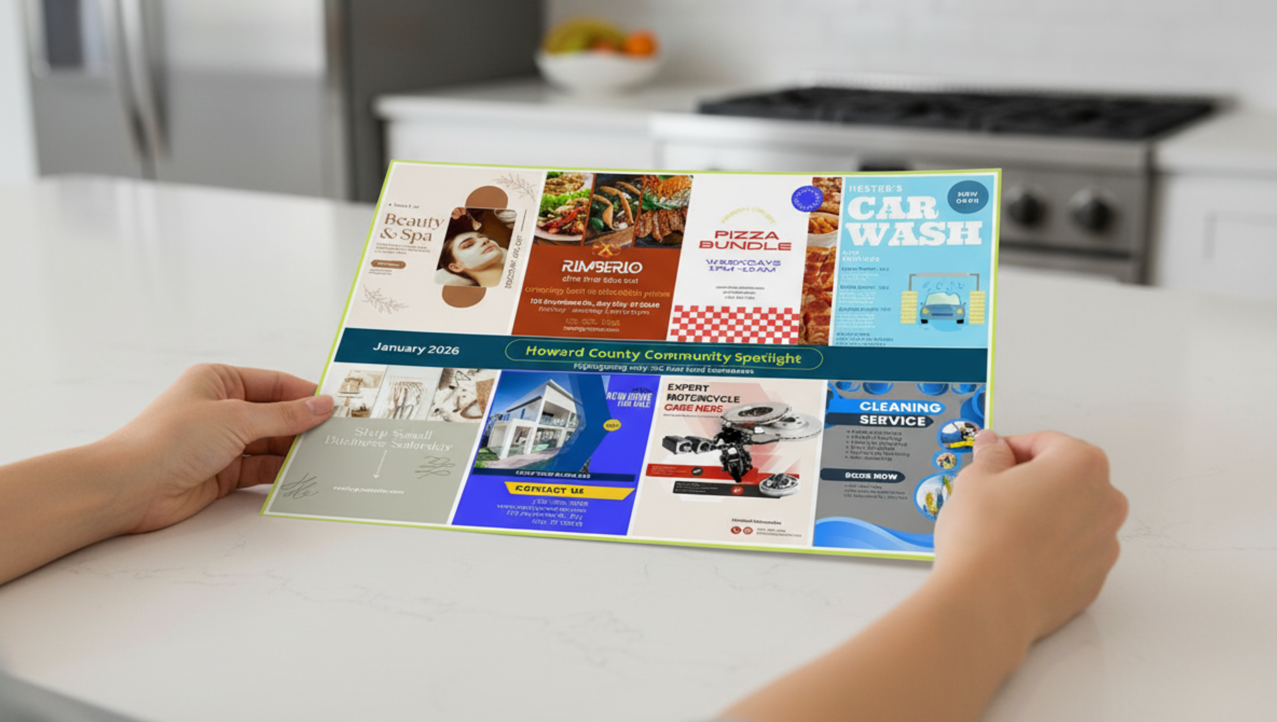 Person holding a colorful community flyer or brochure spread out on a white table in a kitchen, featuring various advertisements and notices.