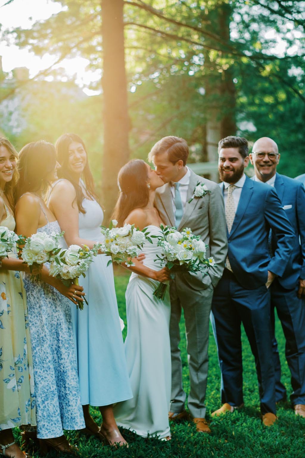 A wedding scene in a forest with a bride and groom kissing, surrounded by bridesmaids and groomsmen.