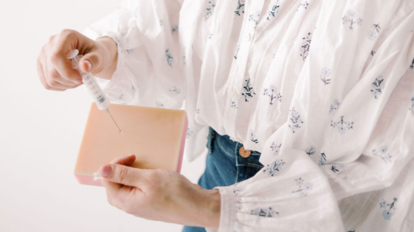 Person holding a bar of soap and preparing to inject it with a syringe.