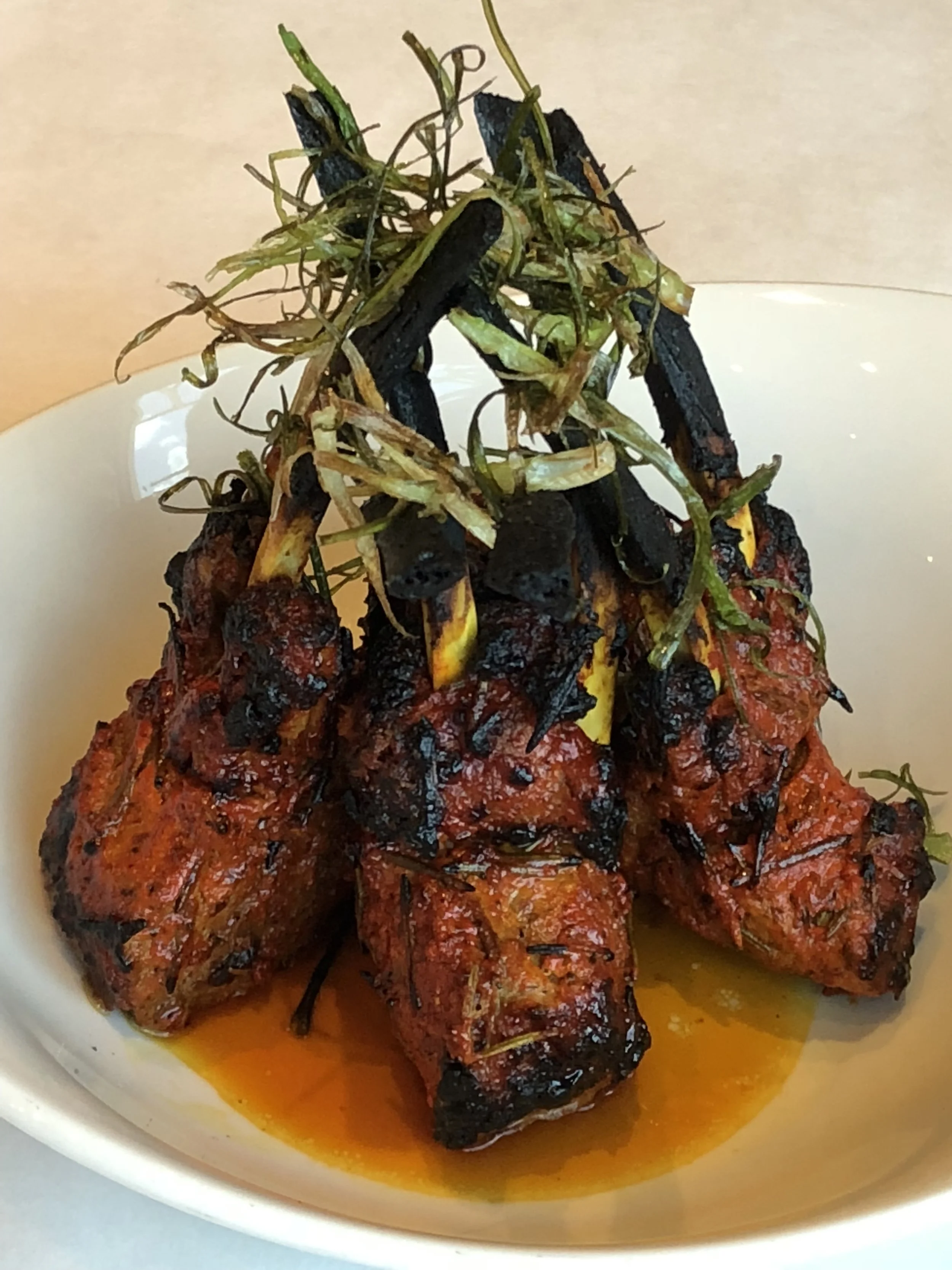 Barbecued ribs garnished with herbs on a white plate.