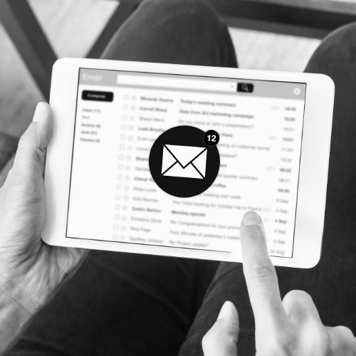 Person holding a tablet displaying an email inbox with a large notification icon showing 12 unread messages