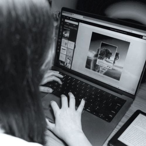 A person working on a laptop, editing a photo with a photo editing software on the screen, while a tablet is placed beside the laptop.