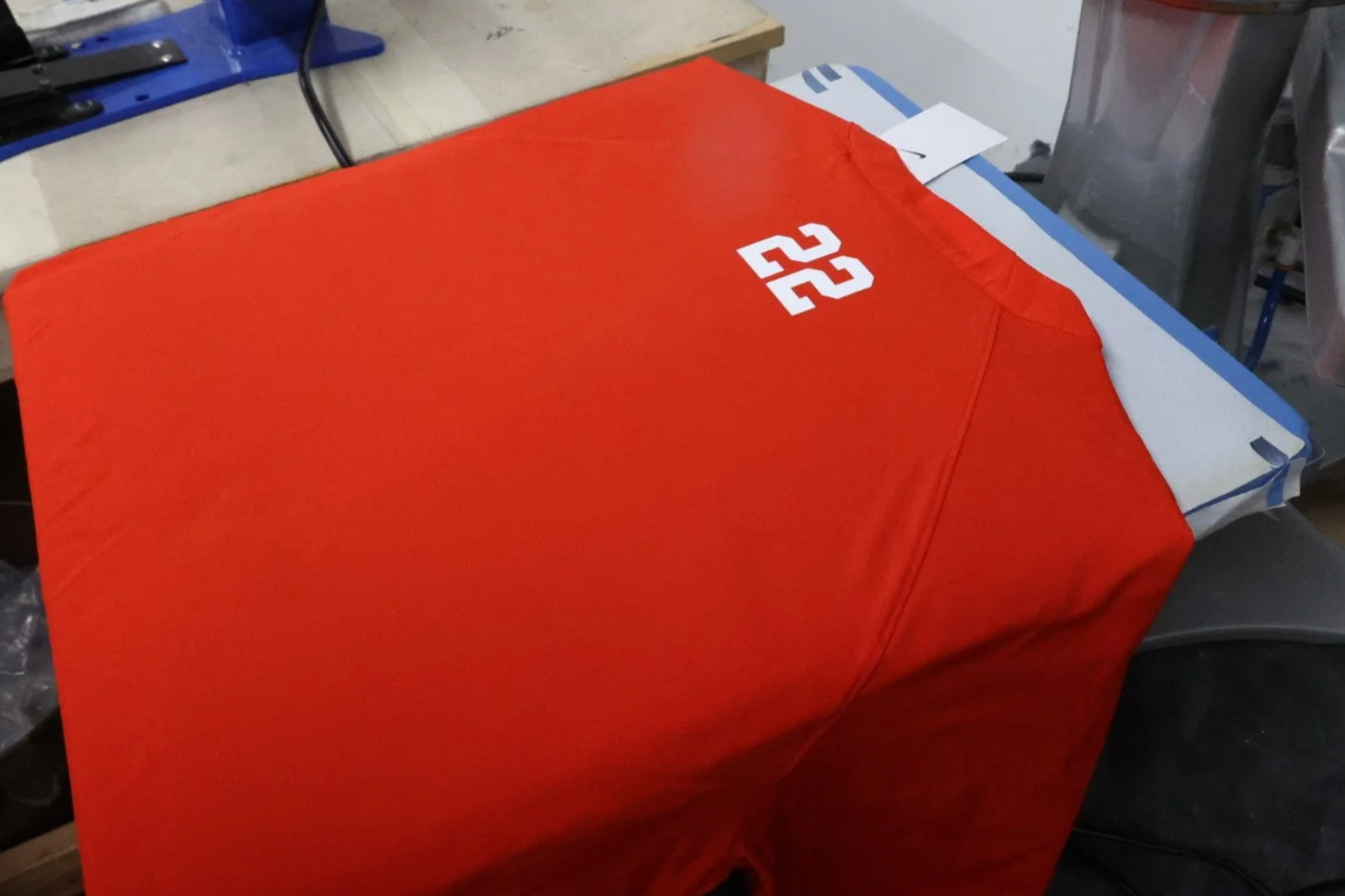 Red sports jersey with the number 22 on it, laying on a cluttered work table.