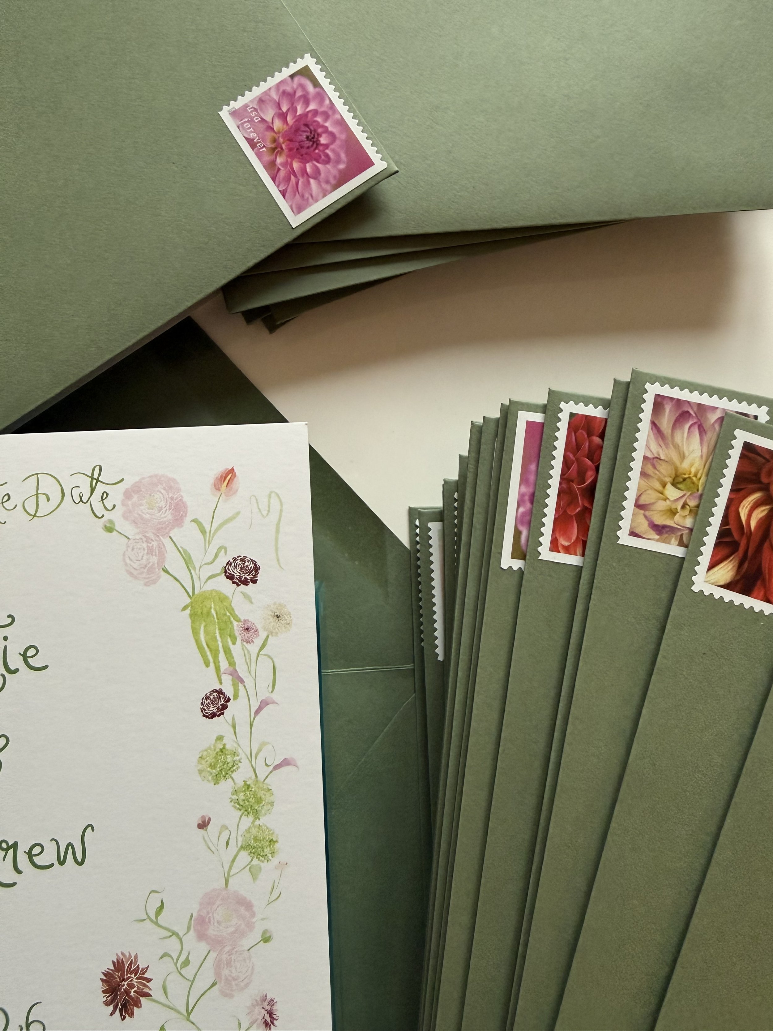Green envelope with custom curated dahlia stamps for a garden wedding
