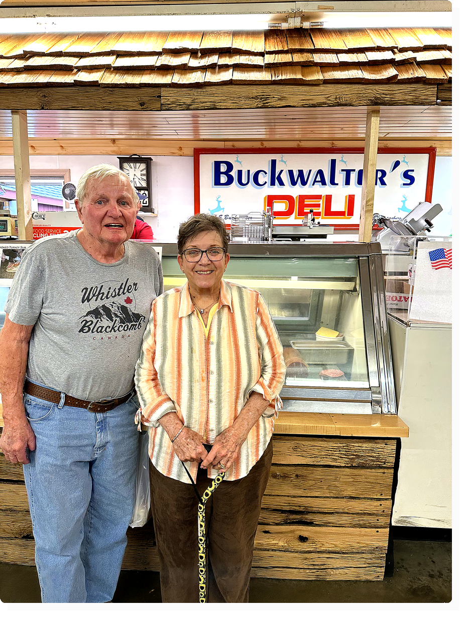 Mary and Gene standing in front of a meat display case at Buckwalter's Deli