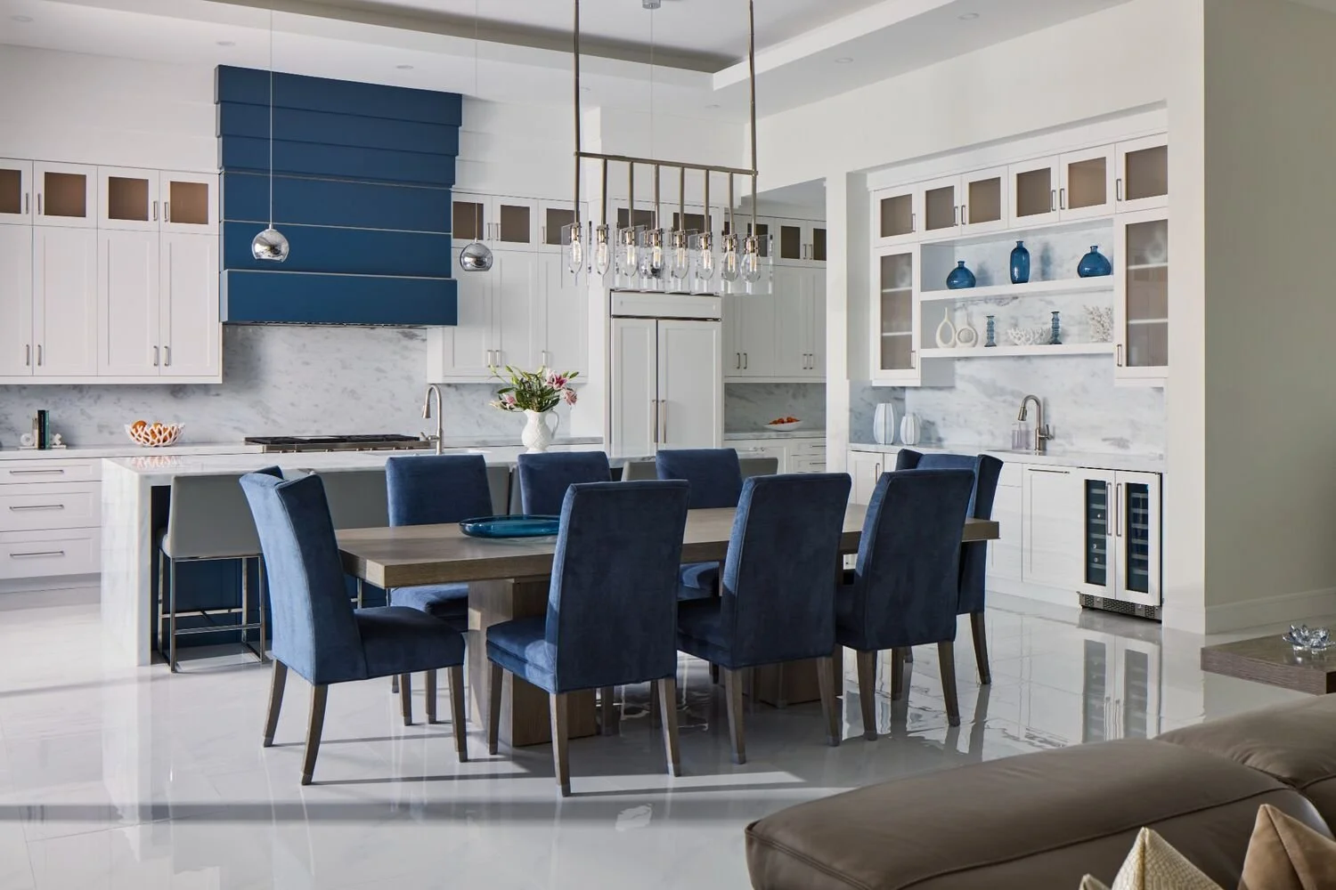 Modern kitchen and dining with white cabinetry, navy accent wall, and polished contemporary finishes