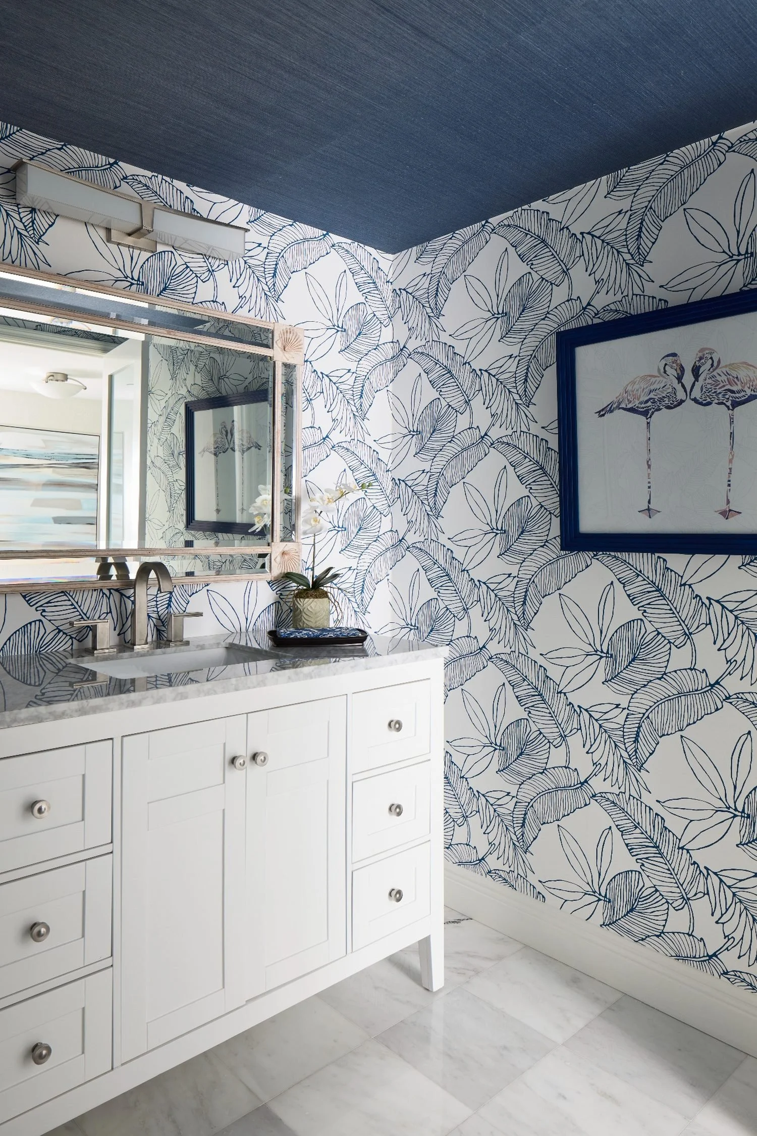 Oceanfront powder bath with blue botanical wallpaper, crisp white vanity, and coastal modern finishes