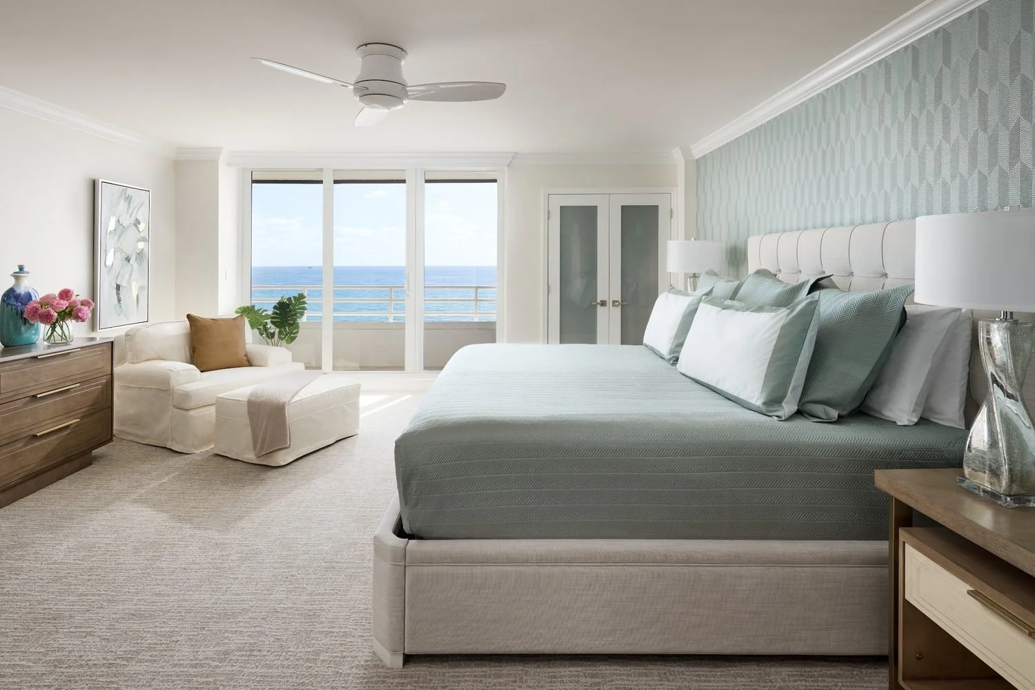 Oceanfront primary bedroom with soft coastal tones, tailored bedding, and airy layered textures