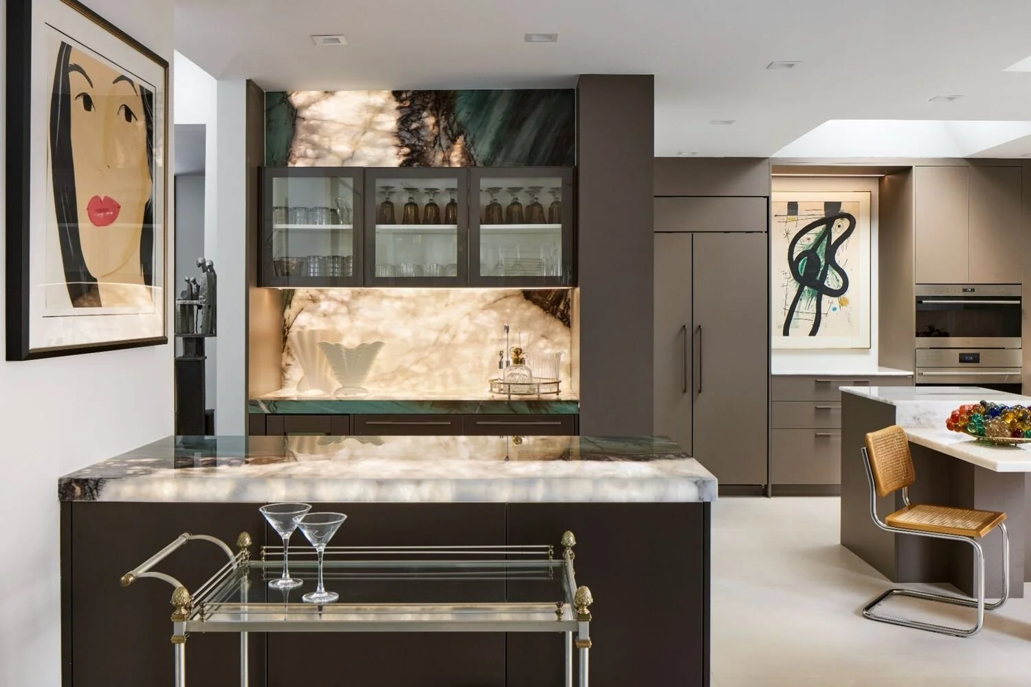 High-end kitchen with warm modern cabinetry, statement stone surfaces, and art-forward design details