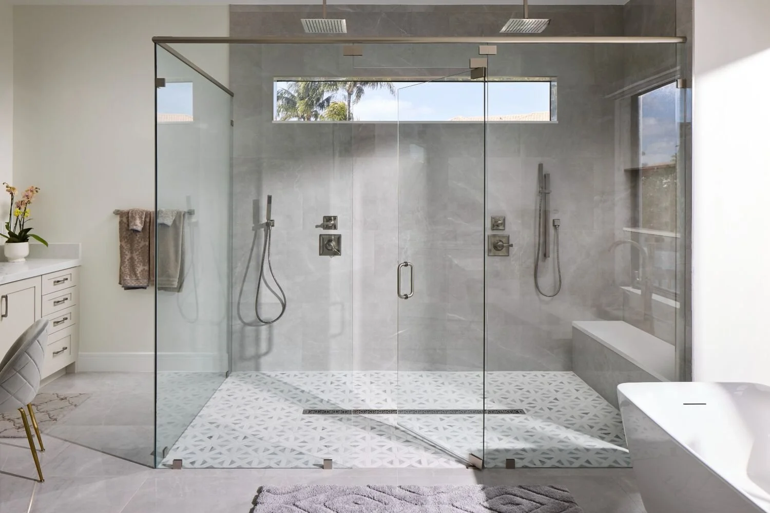South Florida bathroom design with frameless glass shower, gray stone tile, and patterned shower floor