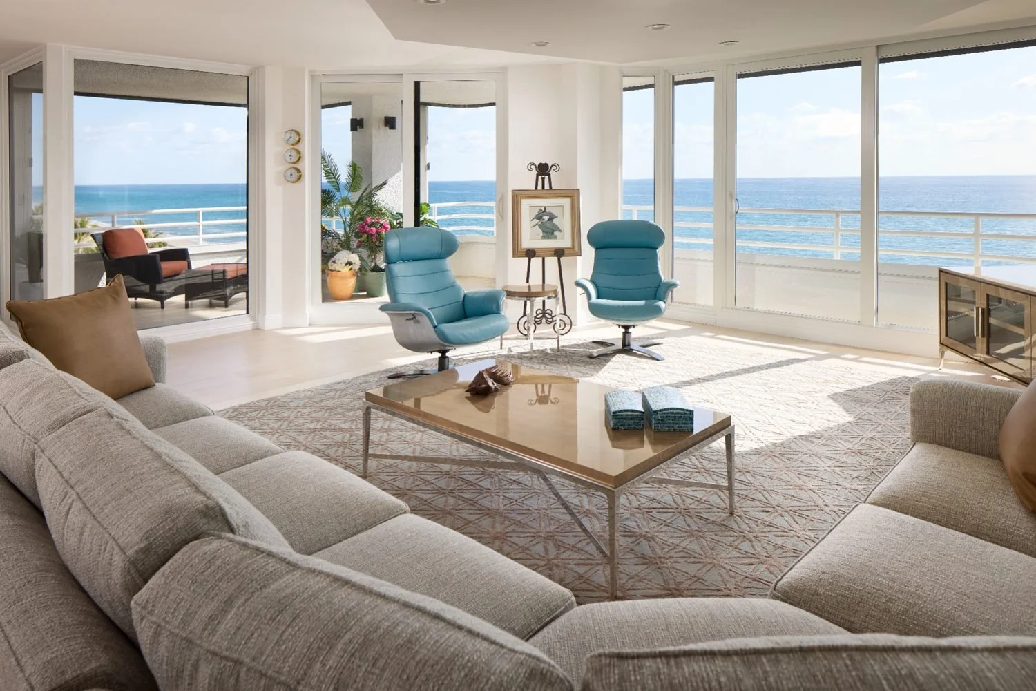 Oceanfront living room with panoramic windows, calm neutral seating, and elevated coastal styling