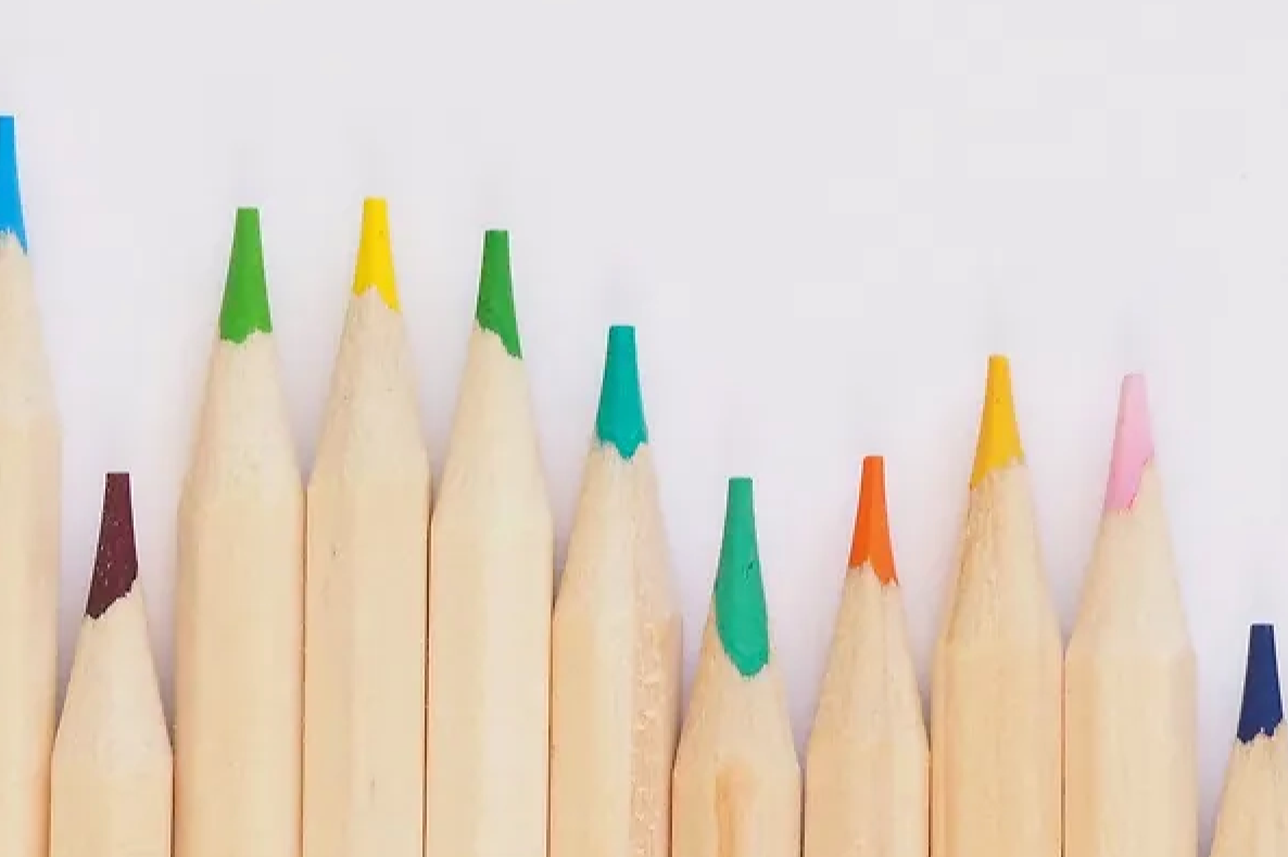 Close-up of colored pencil tips arranged in a row on a white background.