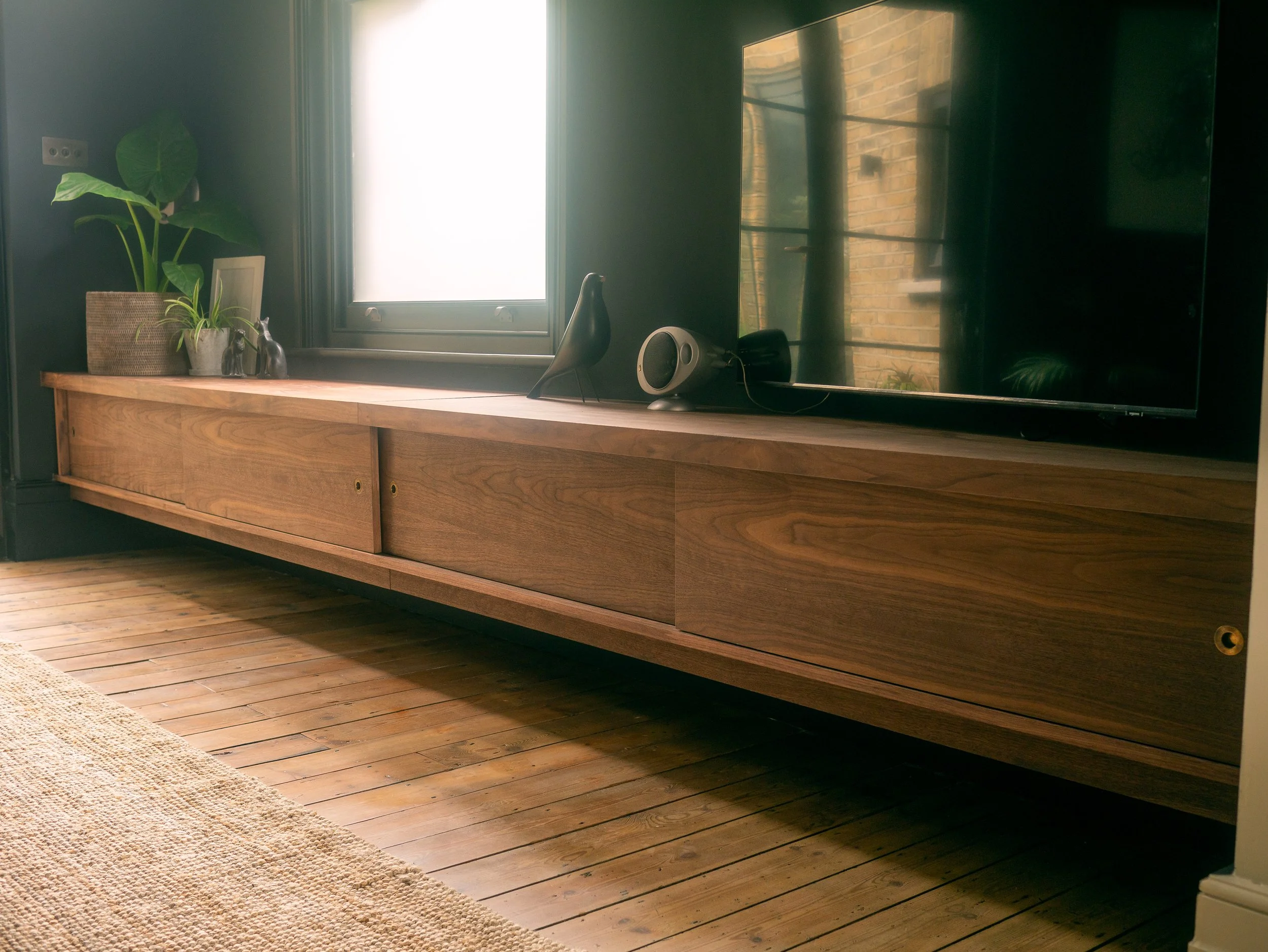 Bespoke minimal contemporary media unit made in solid and veneered walnut with brass pull handles, sliding doors and hidden LED lighting