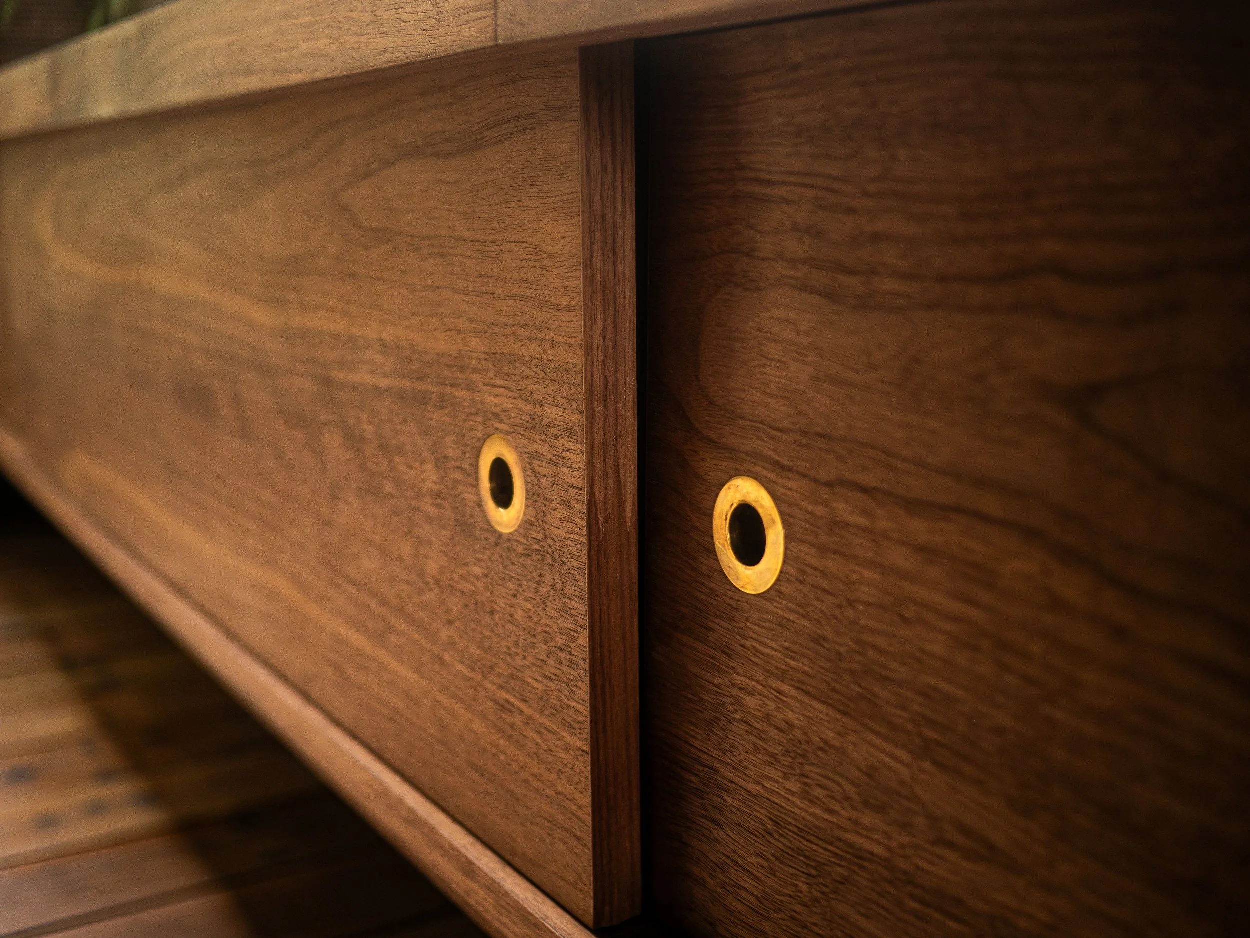 Bespoke minimal contemporary media unit made in solid and veneered walnut with brass pull handles, sliding doors and hidden LED lighting
