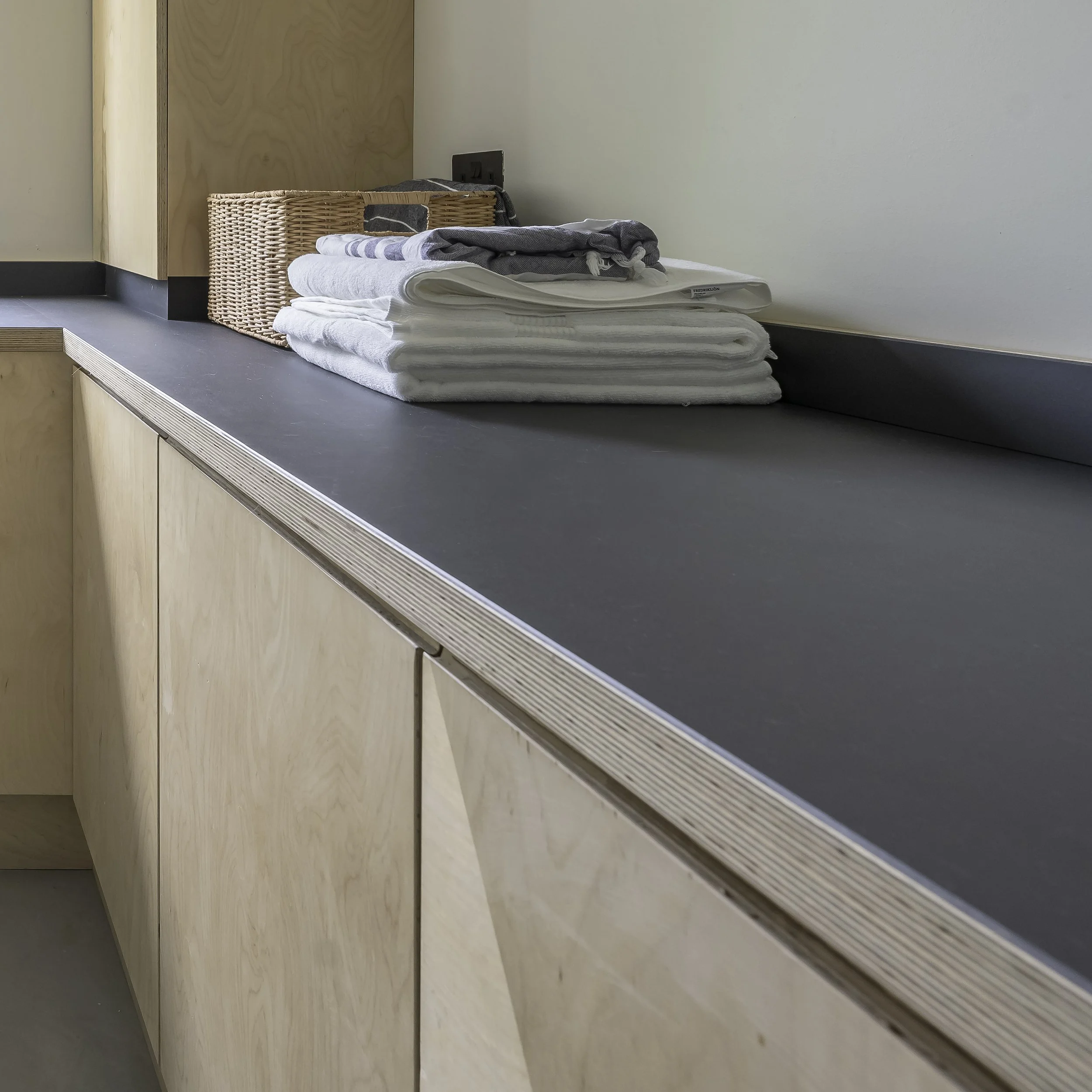 Bespoke utility cabinetry in birch plywood with counter tops finished in Forbo furniture grade Lino. 'J' groove handles