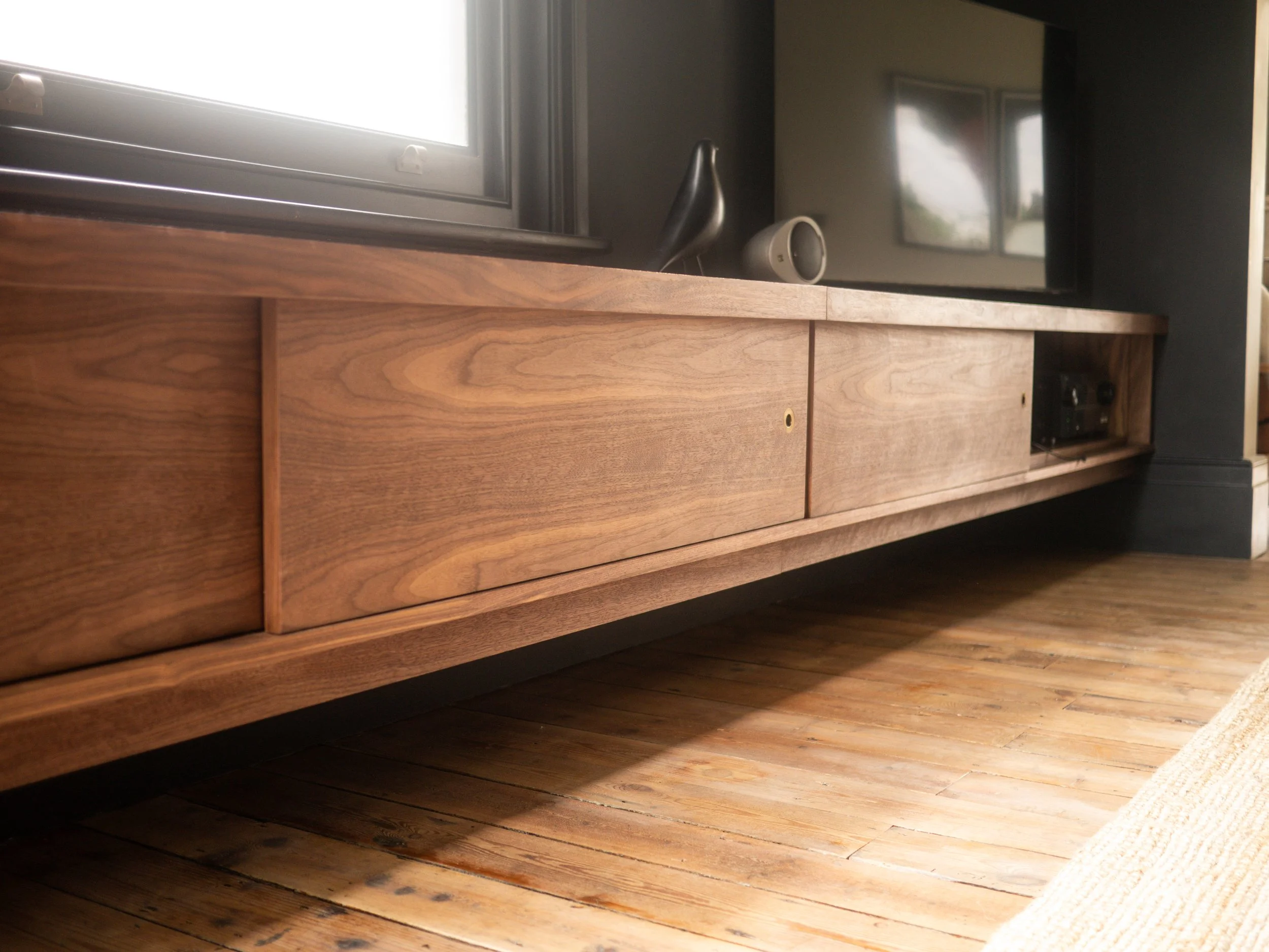 Bespoke minimal contemporary media unit made in solid and veneered walnut with brass pull handles, sliding doors and hidden LED lighting