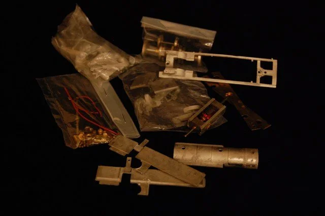 Various small mechanical and electronic parts scattered on a black surface.