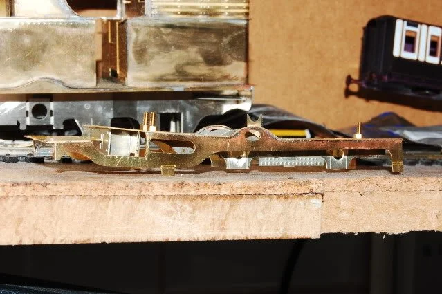Close-up of a metal clock movement or watch mechanism on a workbench.