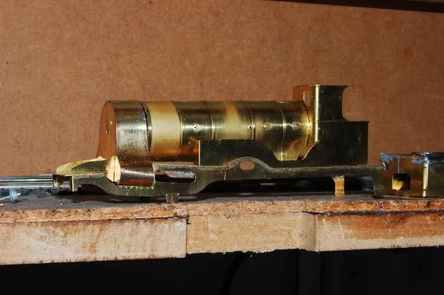 Close-up of a vintage brass and metal toy train engine placed on a wooden surface.