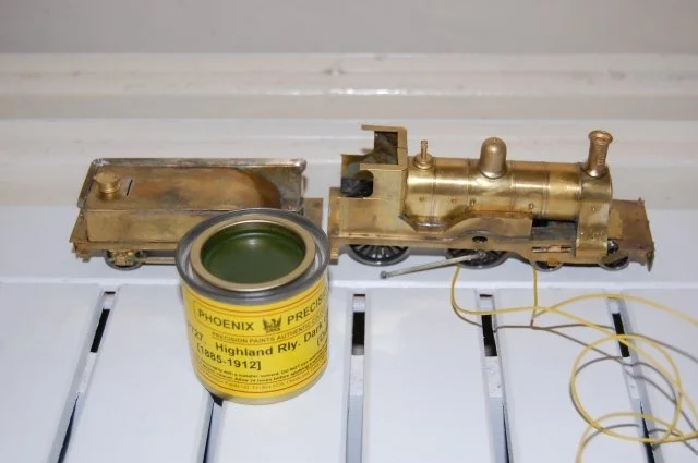 Model train engine and tender with a can of paint or lubricant in front of them.