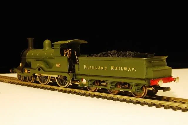 Model green railway steam locomotive with a tender marked 'HIGHLAND RAILWAY' on a track.