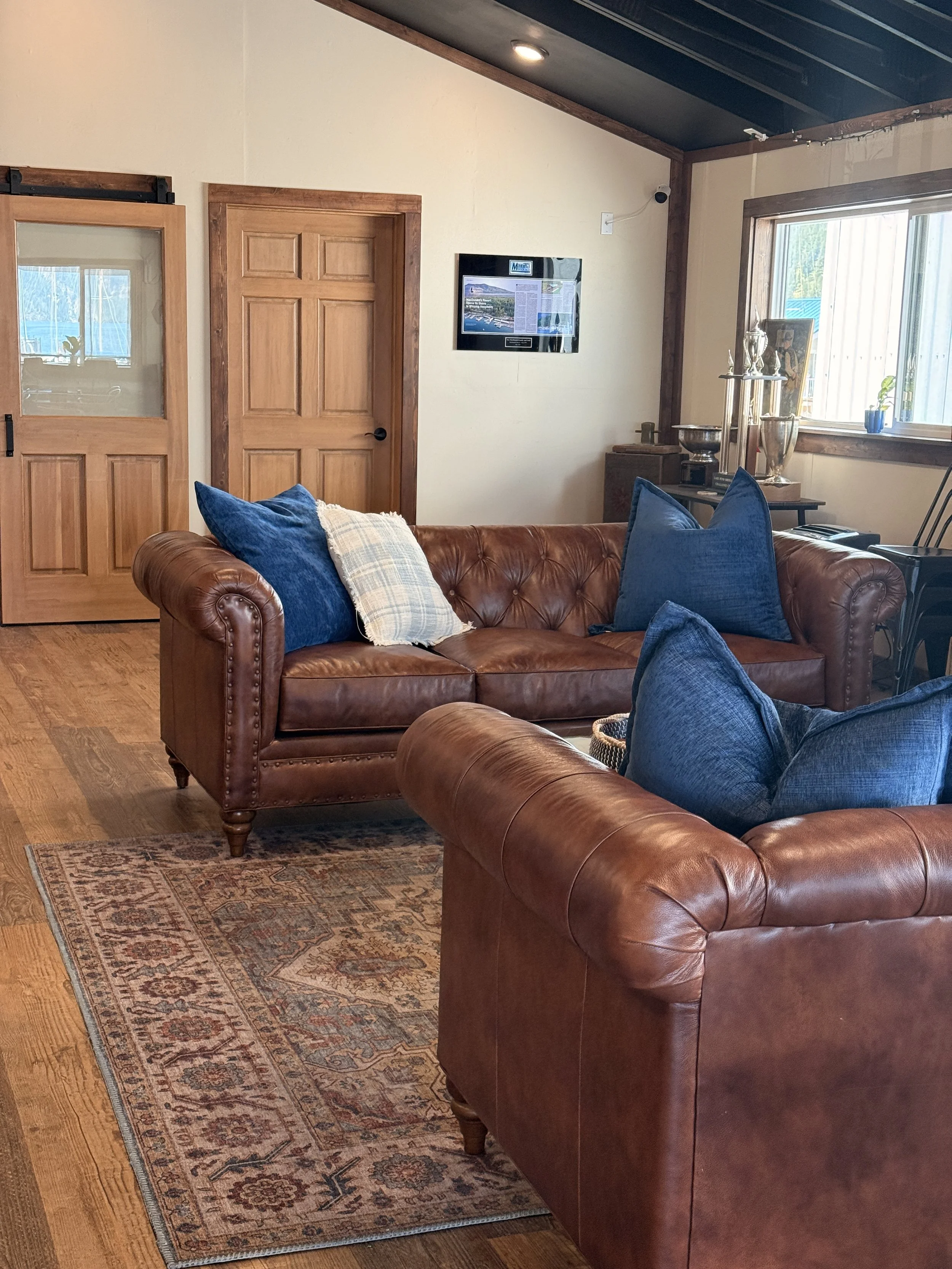 Custom café lounge design featuring vintage leather sofas, layered rugs, and rustic commercial styling in Bayview Idaho.